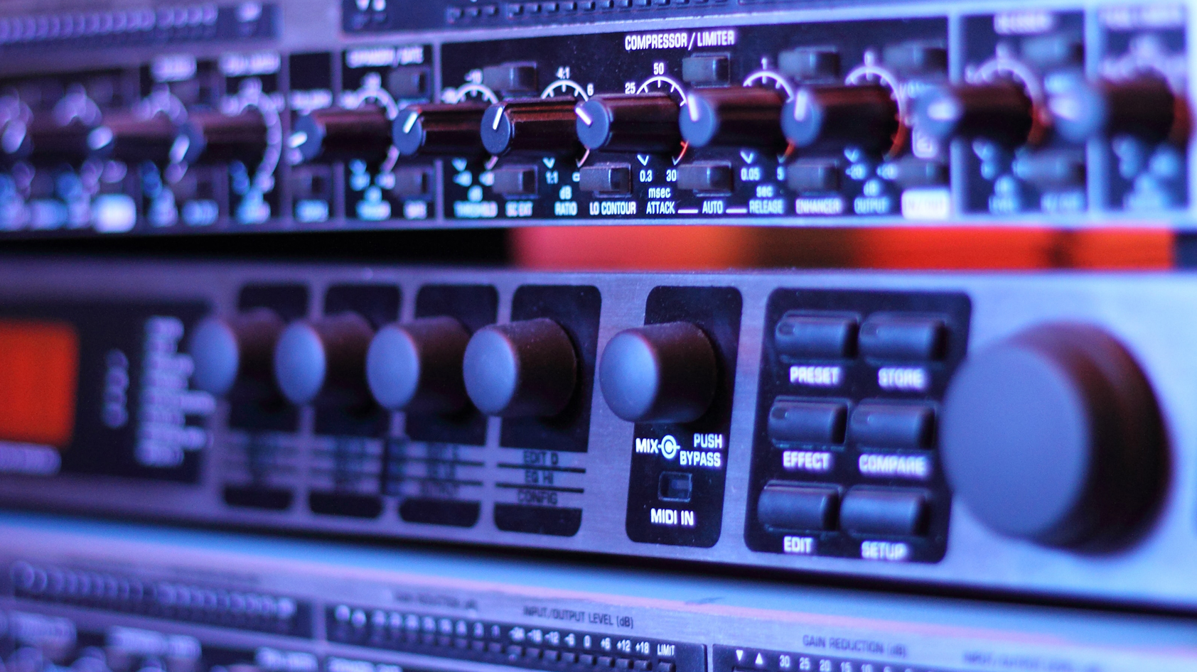 A close up of a studio channel strip showing a hardware compressor and other tools.