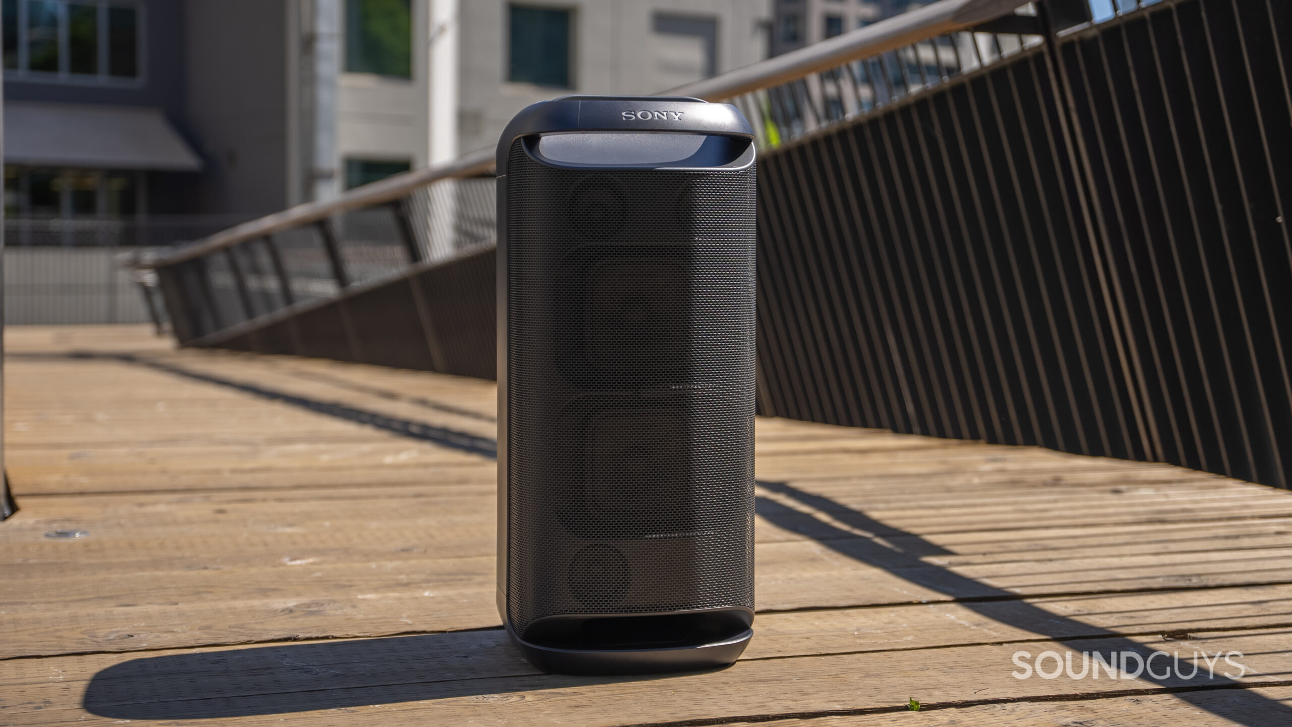 The Sony SRS-XV800 sitting outside on a wooden surface with railing in the background.