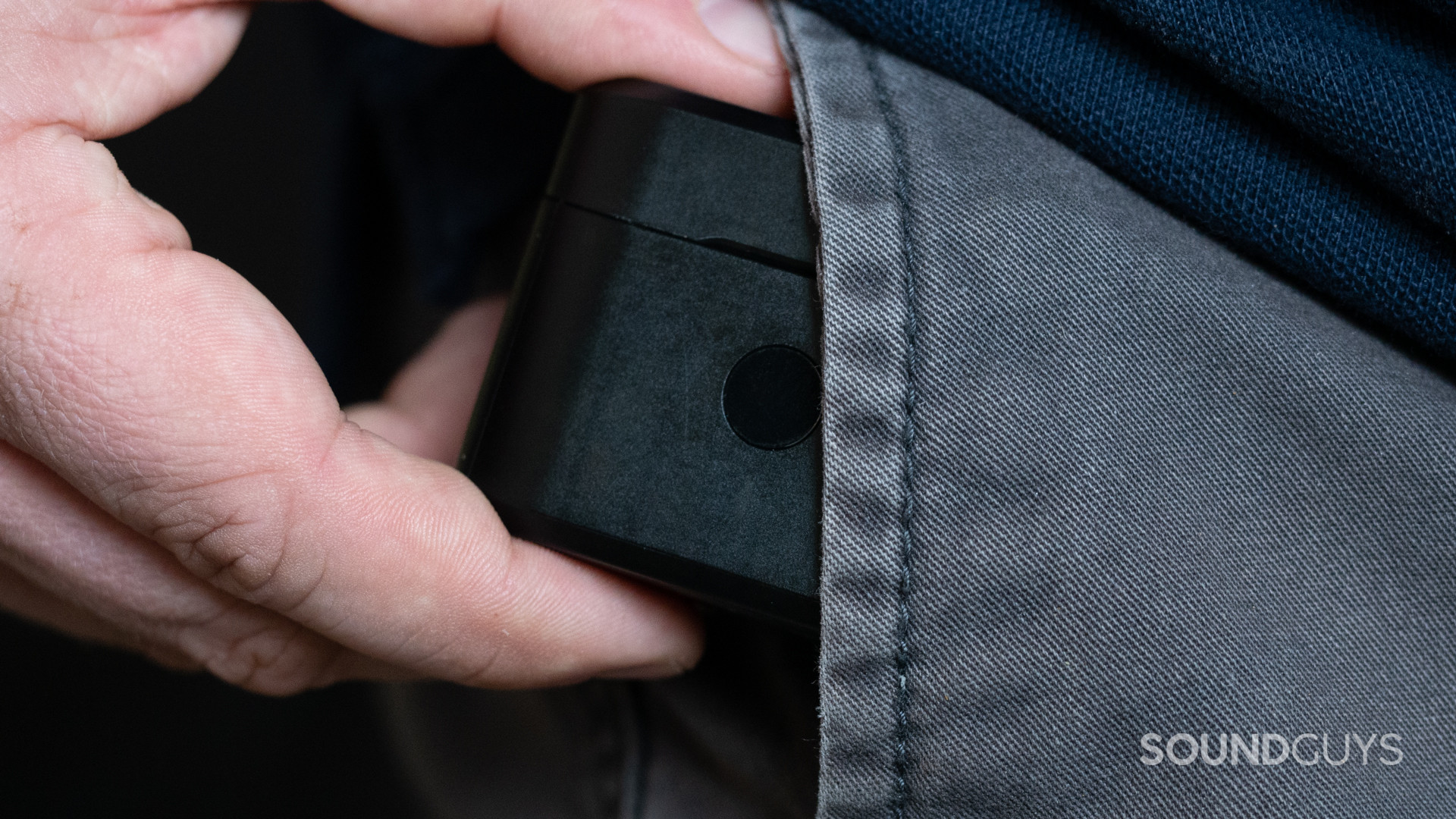 A photo of someone jamming the large charging case of the HyperX Cirro Buds Pro into their pocket.