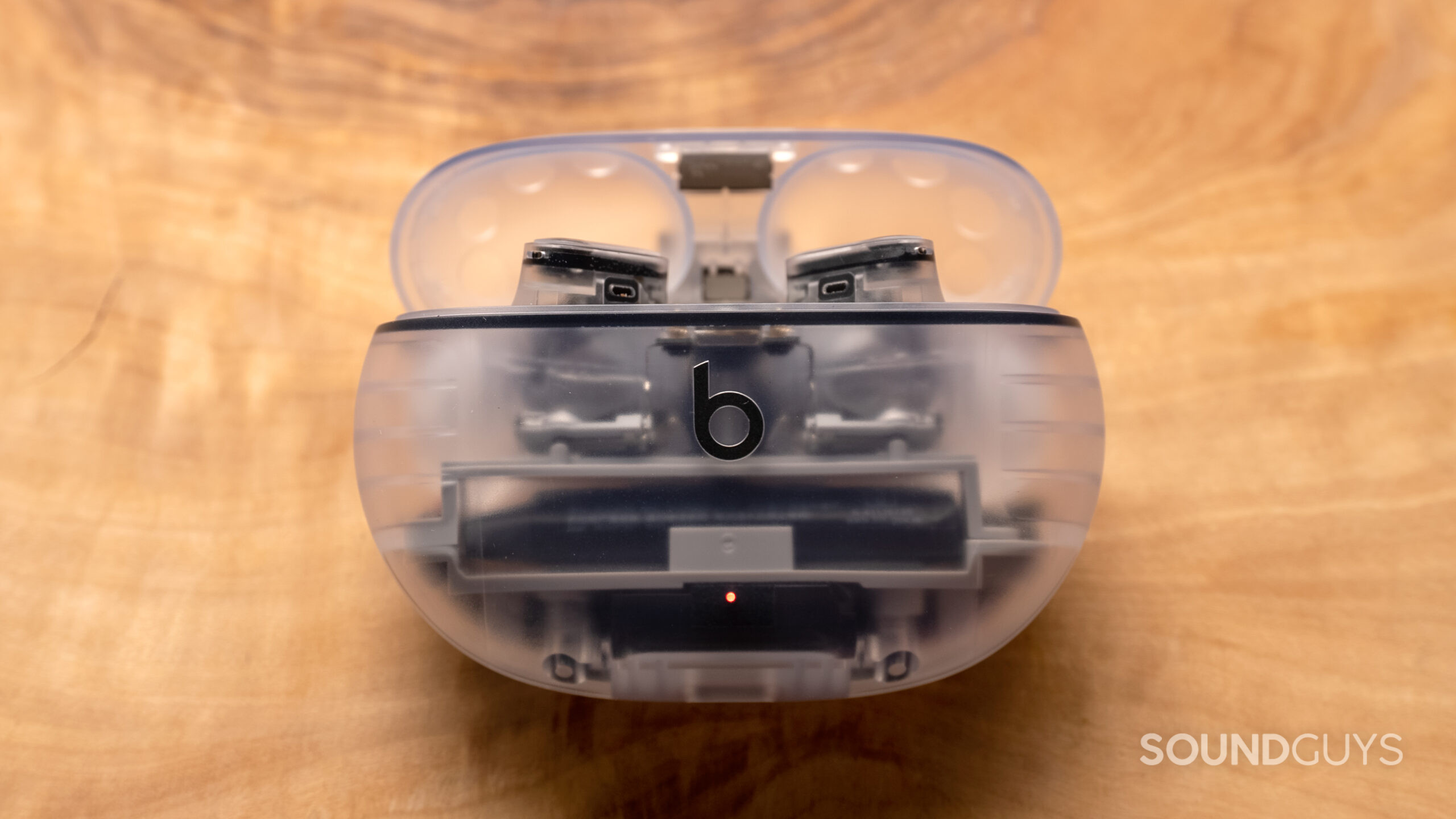 Image of a Beats Studio Buds Plus transparent case resting on a wooden surface