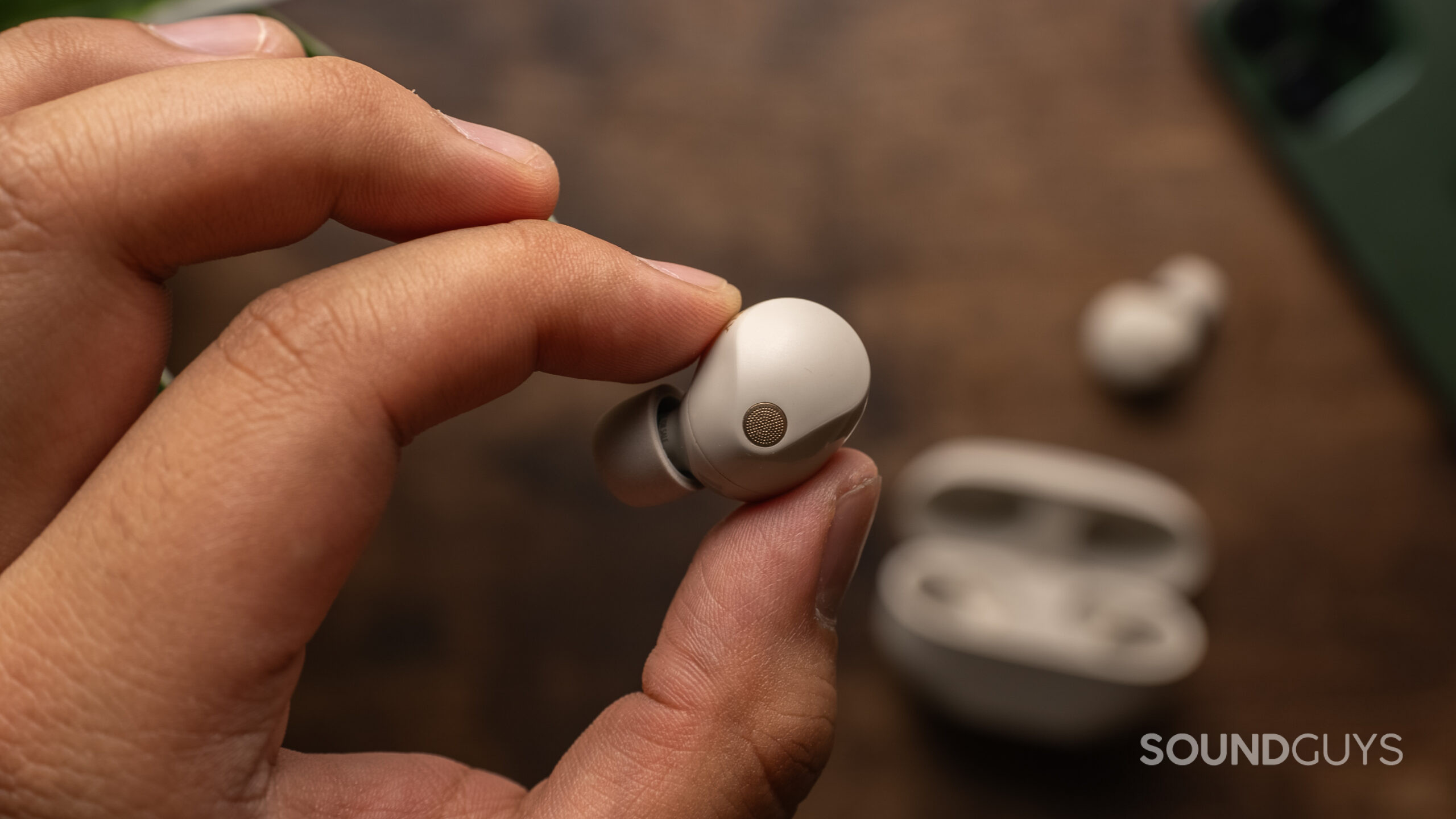 Holding the left earbud of the Sony WF-1000XM5 in hand
