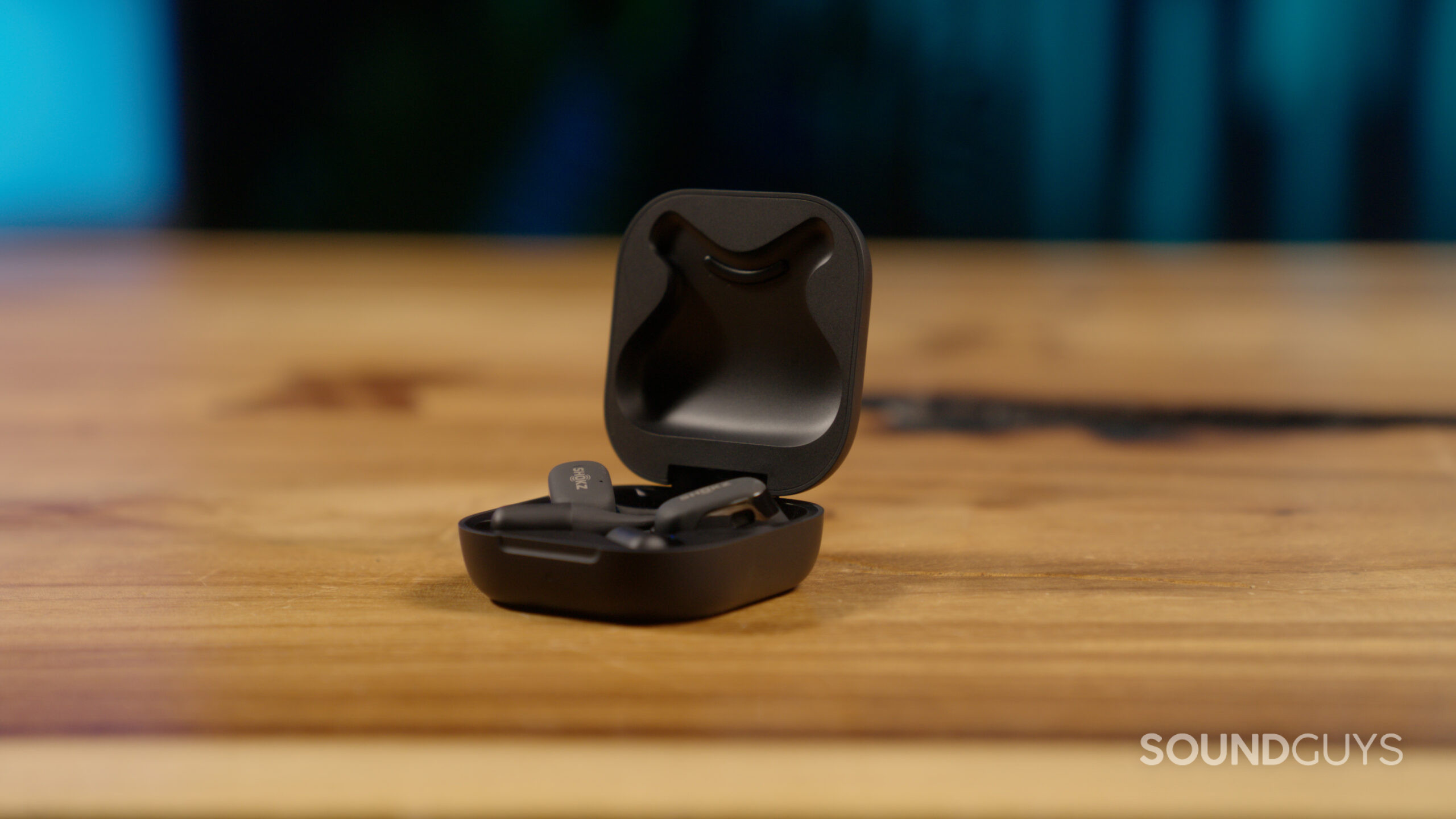 On a wood surface the Shokz OpenFit rests with the lid open.