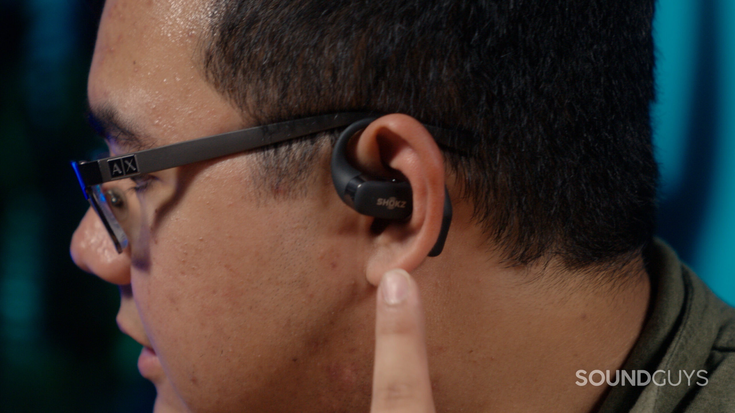 A man faces left wearing the Shokz OpenFit about to use the touch control.