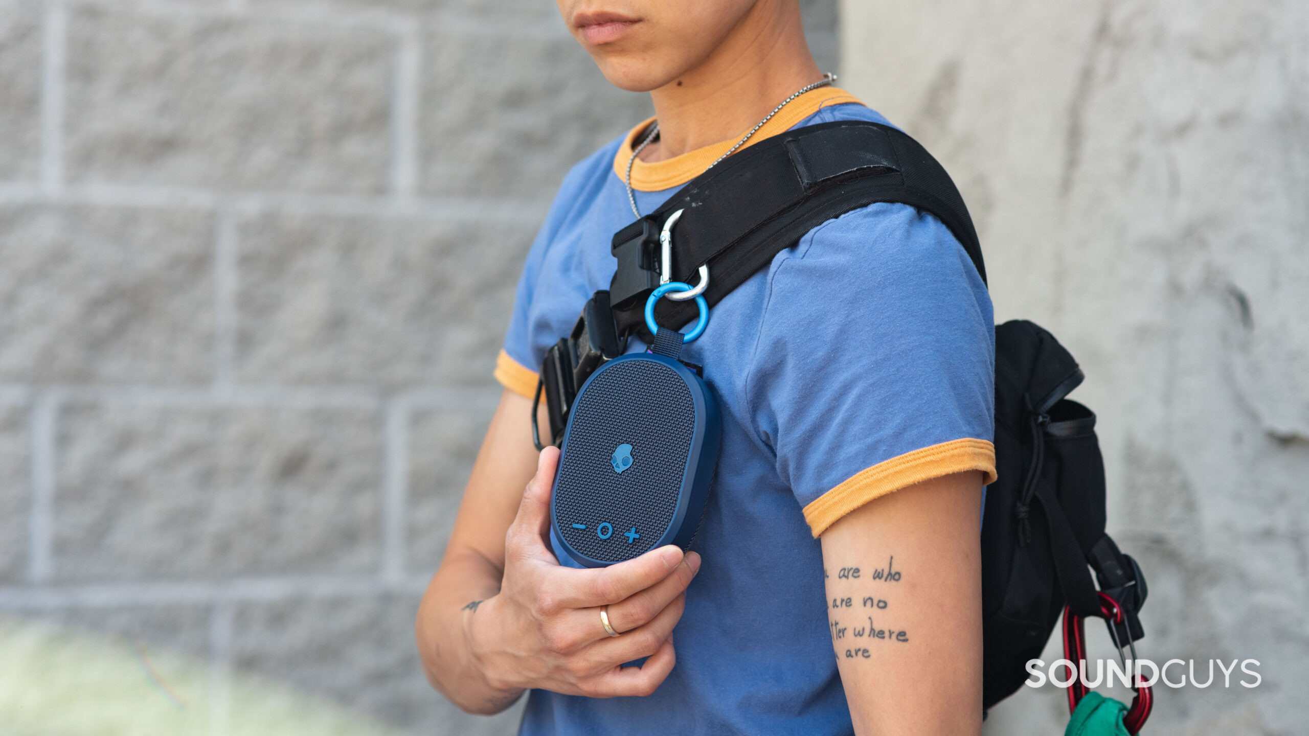A person wears the Skullcandy Kilo speaker on a sling bag.