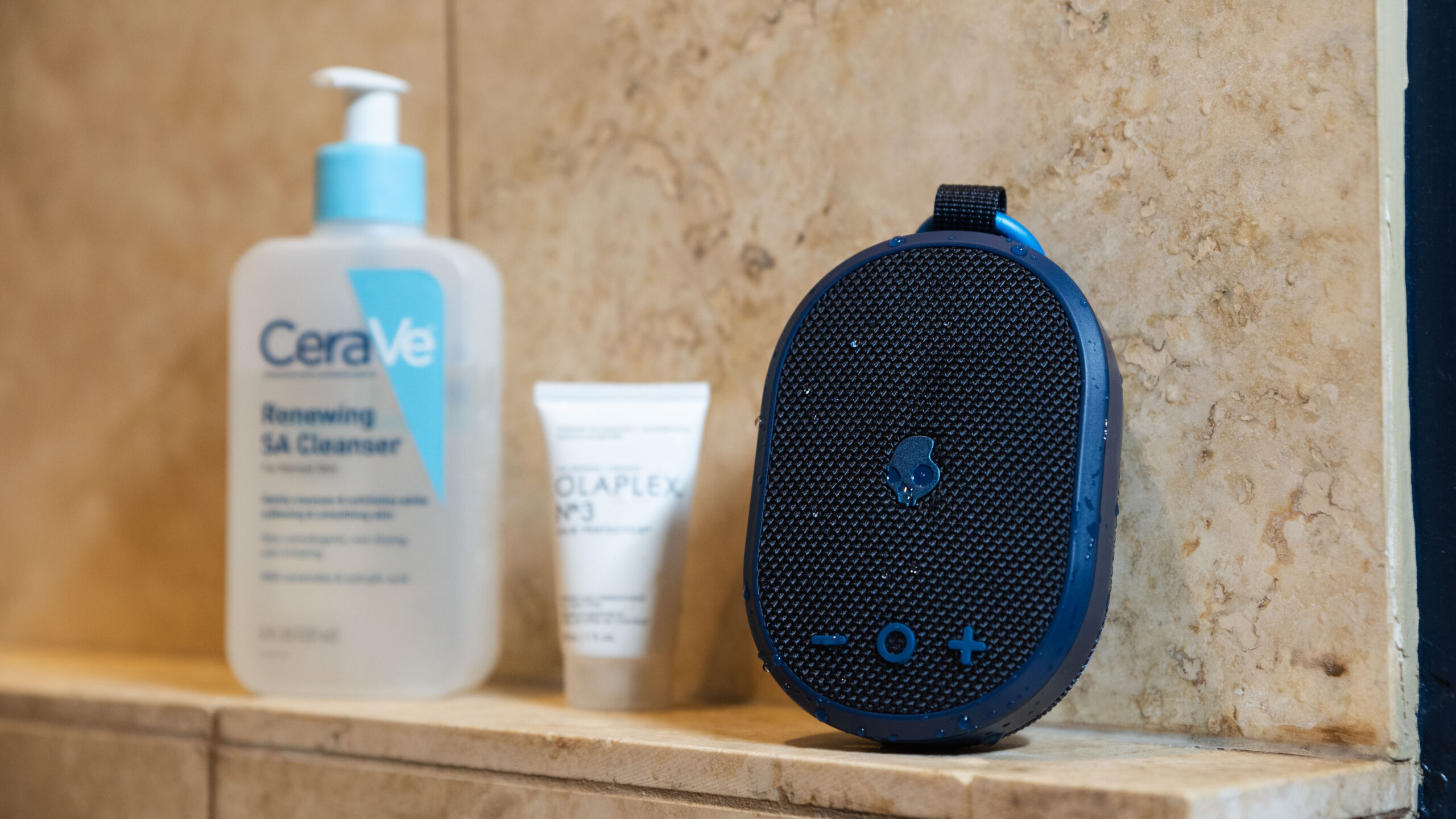 The Skullcandy Kilo speaker with water droplets in a shower setting.