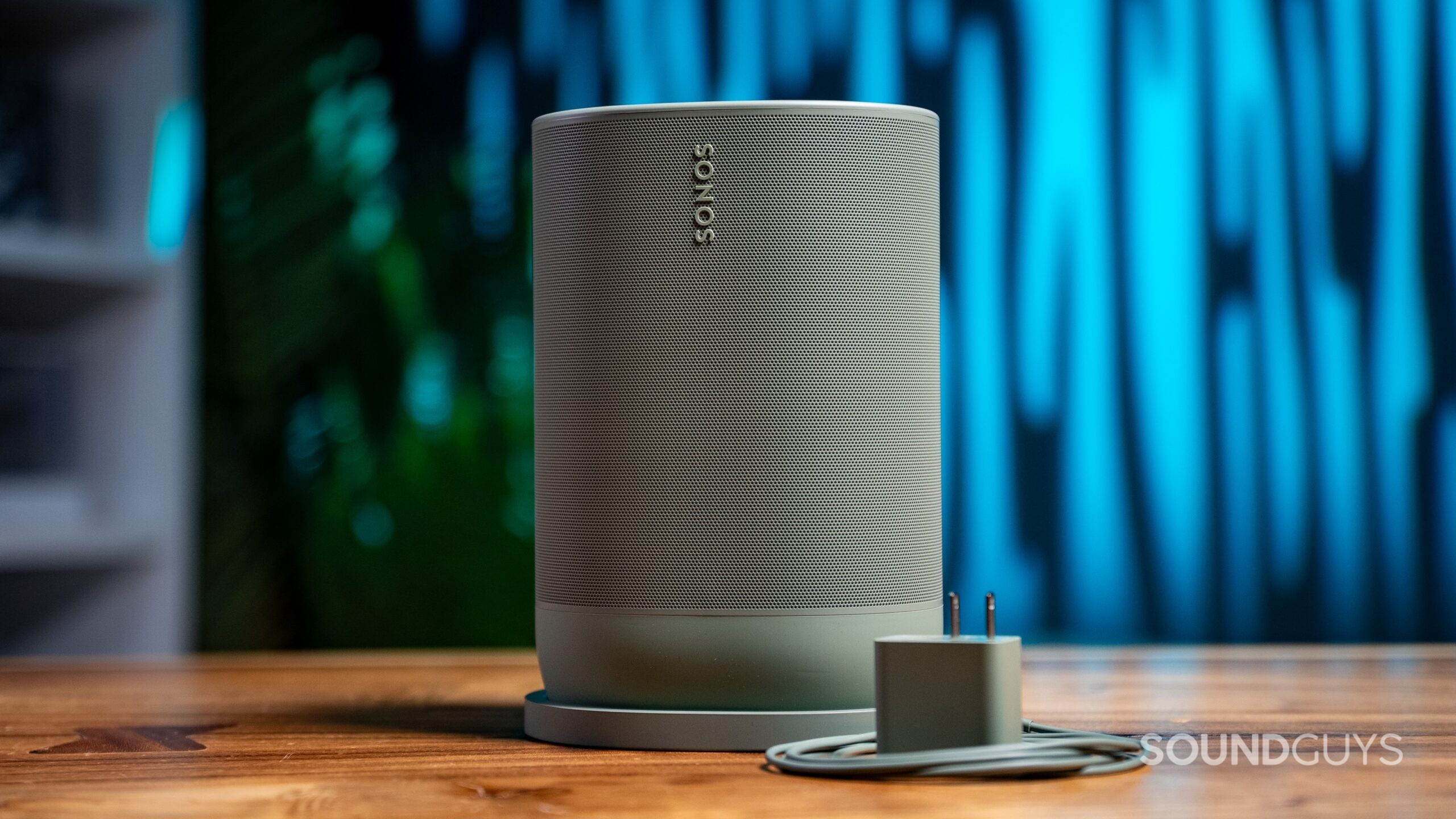 The Sonos Move 2 in Olive shown with included charging accessories with a blue background.