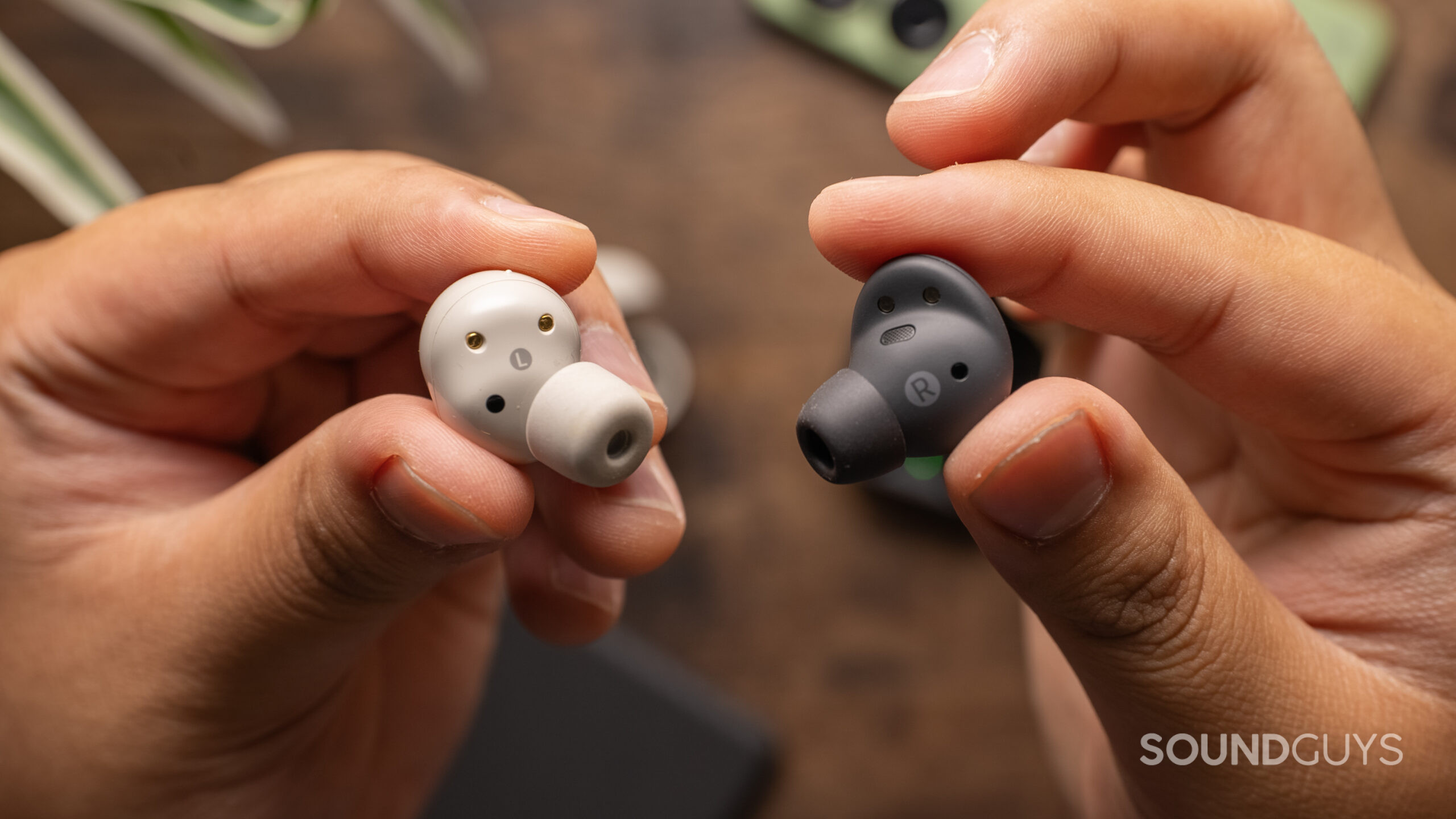 Two hands hold one of the Sony WF-1000XM5 and Samsung Galaxy Buds 2 Pro showing the inside housing and ear tips.