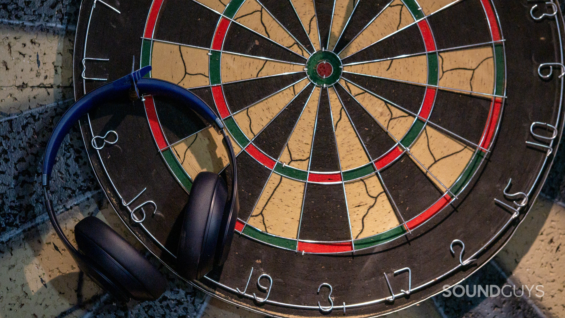 The Beats Studio Pro hanging from a dart, thrown aside of the dartboard.