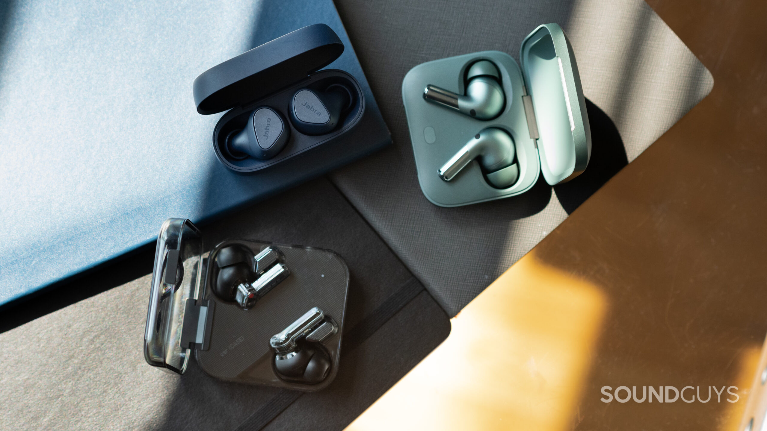 The Jabra Elite 4, OnePlus Buds Pro 2, and Nothing Ear 1 earbuds in their open cases.