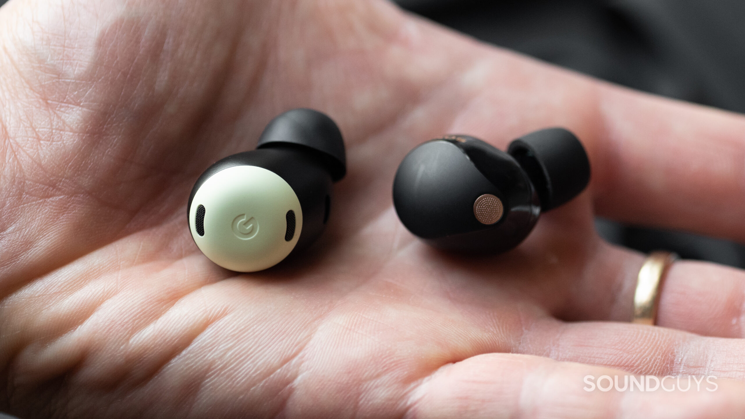 A hand holds the Pixel Buds Pro and WF-1000XM5 earbuds.