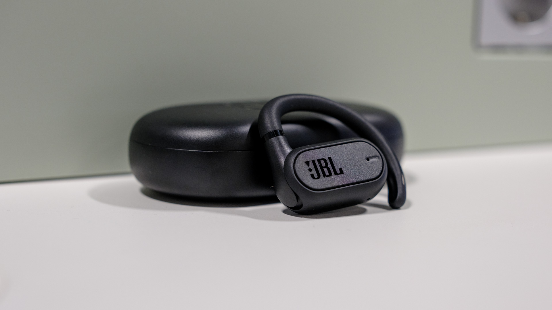 jbl soundgear sense earbud in front of charging case