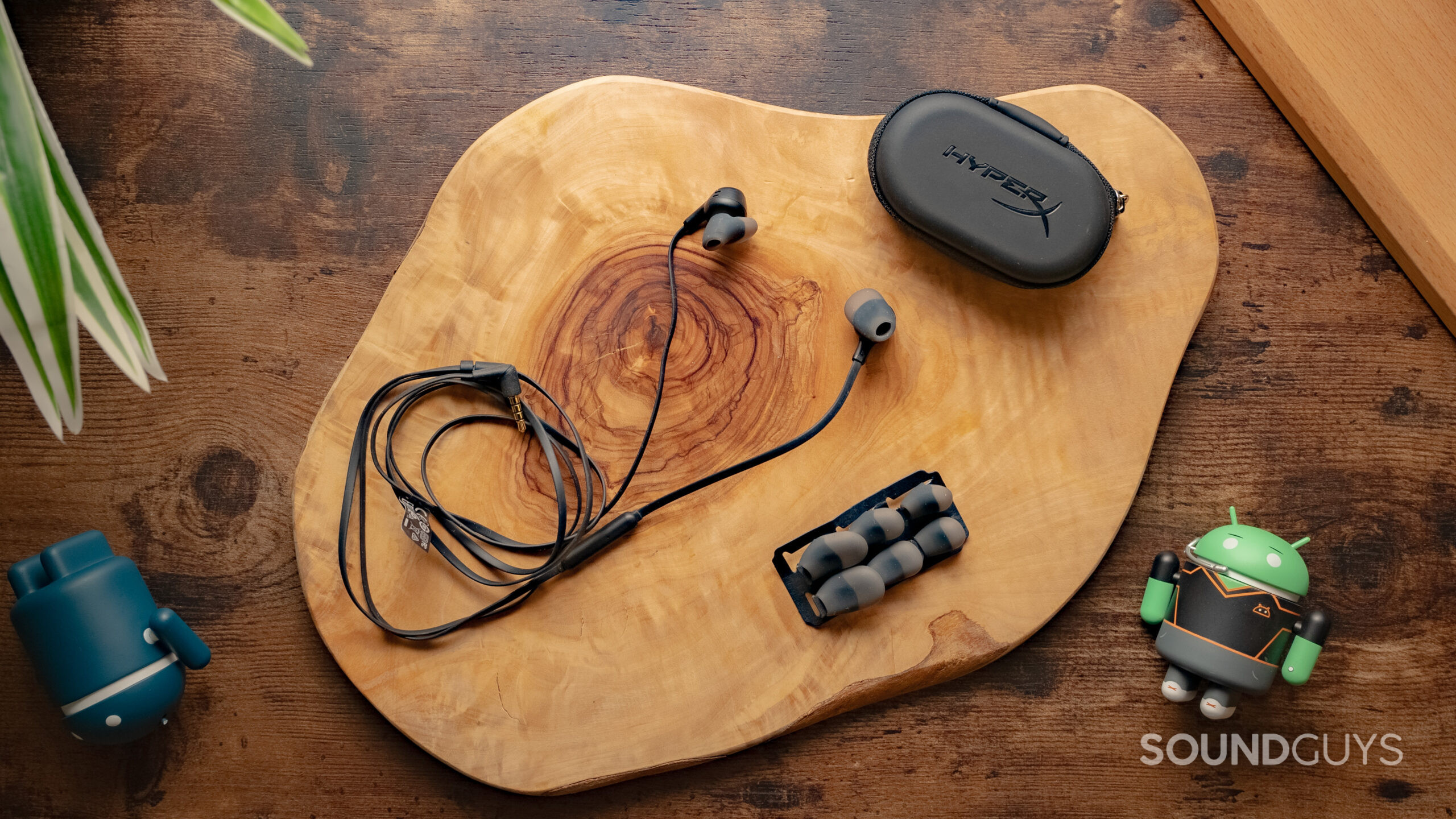 The HyperX Cloud Earbuds II sitting on a wooden table with the carrying case and different ear tips clearly visible.