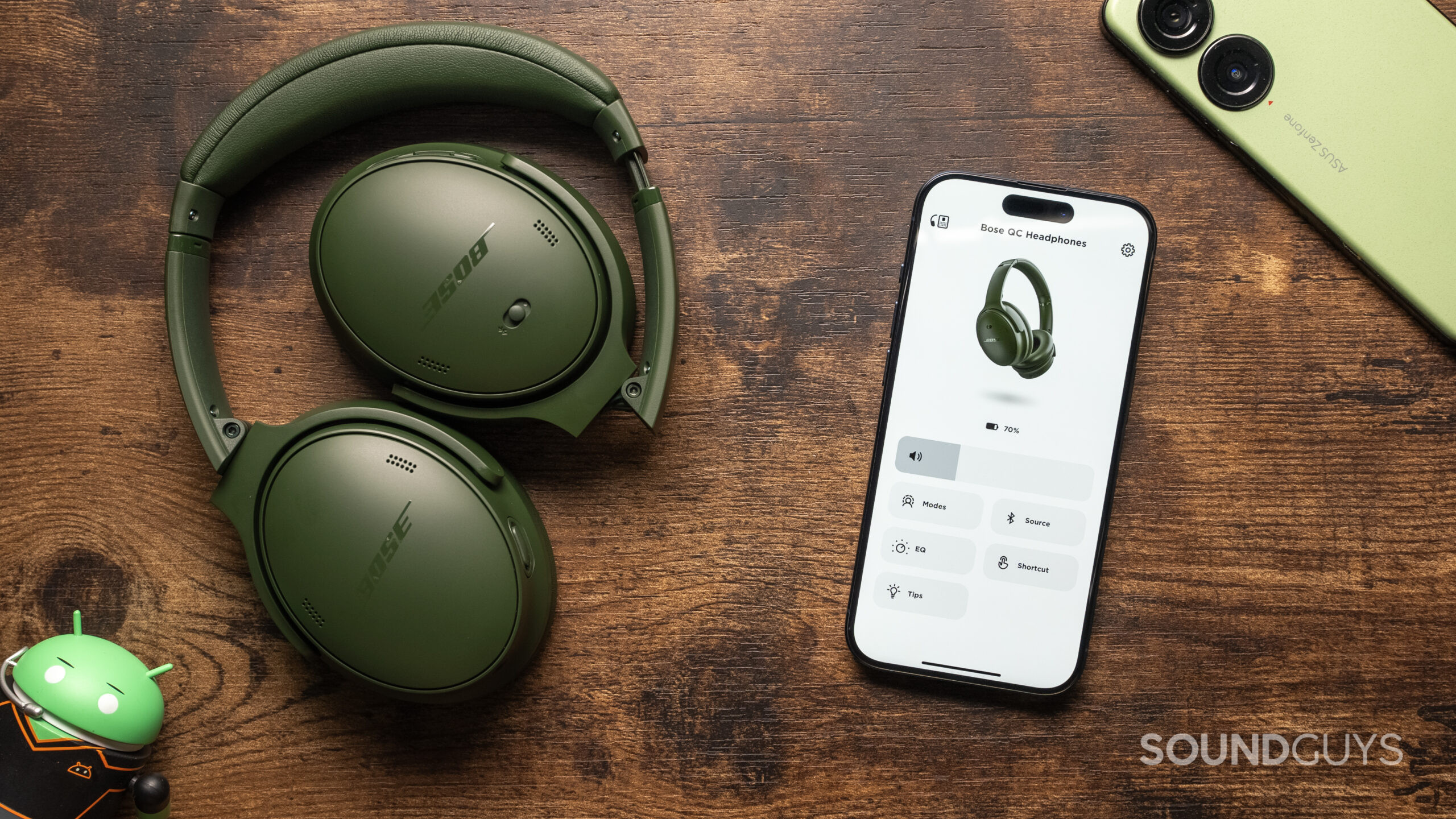 The Bose QuietComfort Headphones sitting atop a table, with the Bose Music App open on a phone.