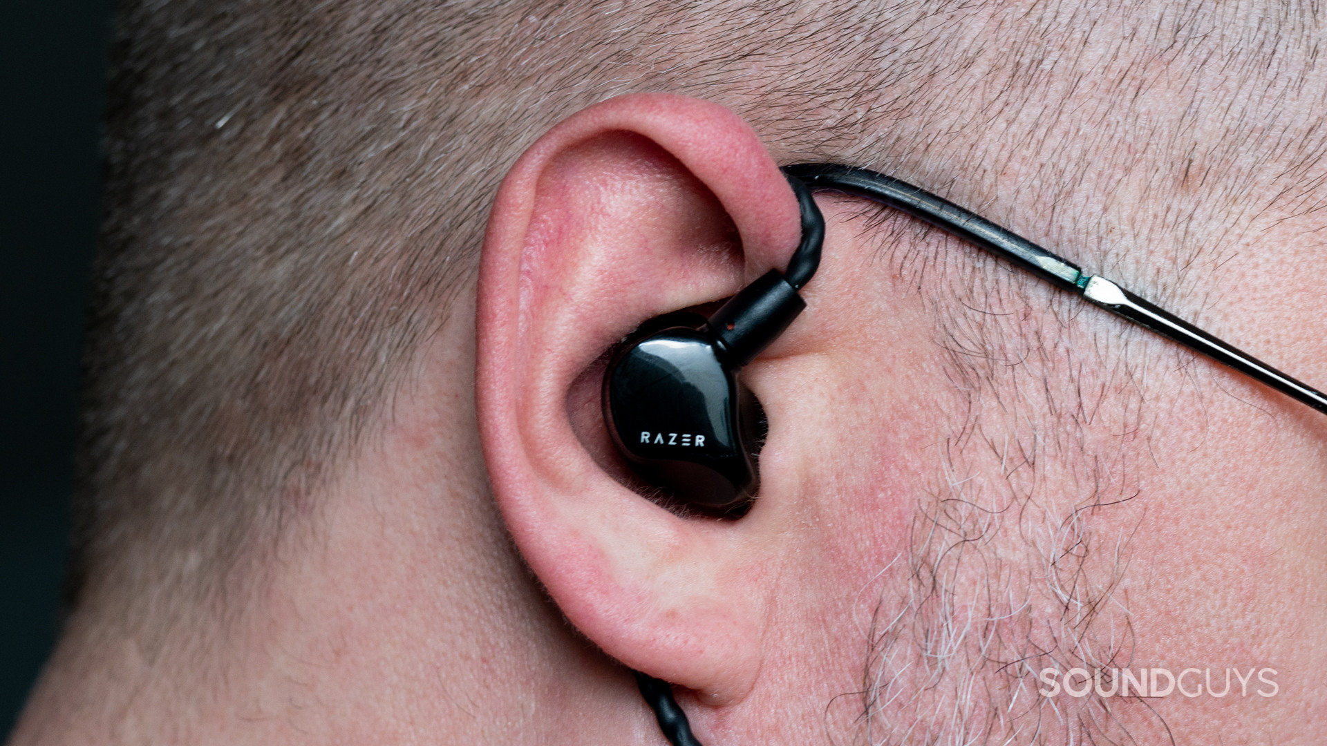 The Razer Moray IEM being used by a short-haired, bespectacled man.