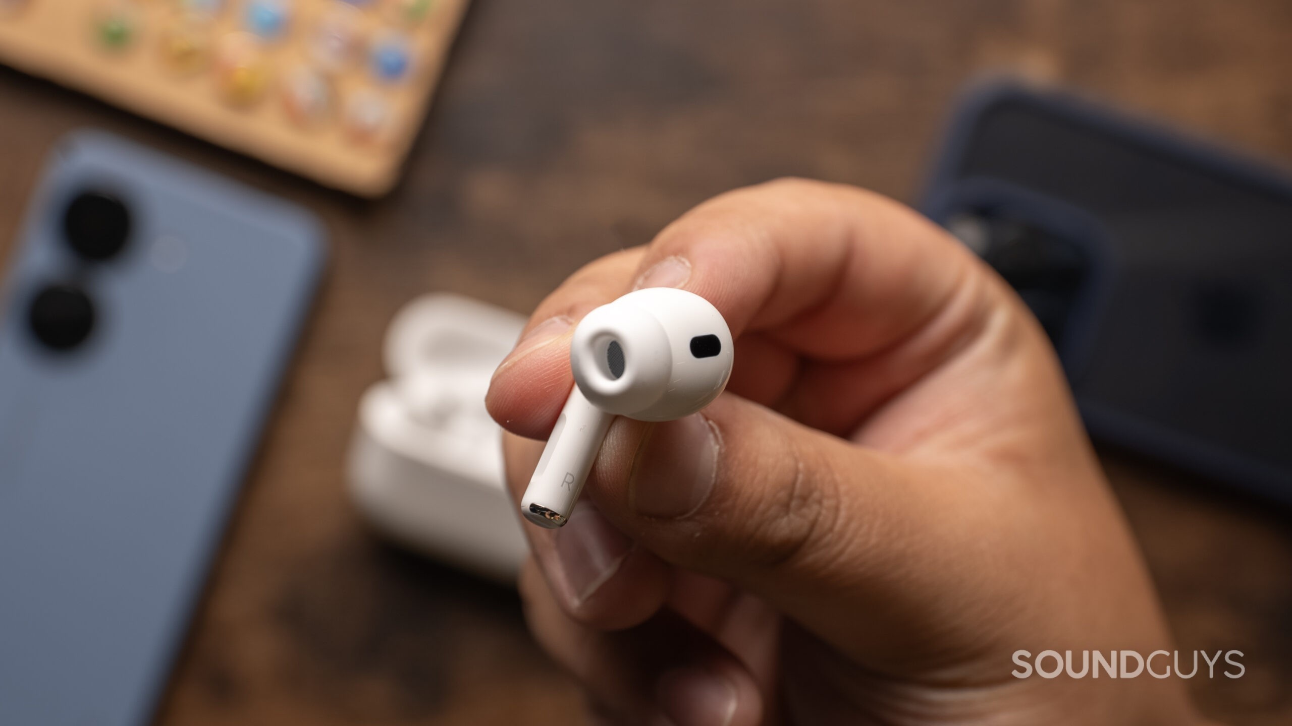 A hand holds the Apple AirPods Pro (2nd generation) bud showing the ear tips.