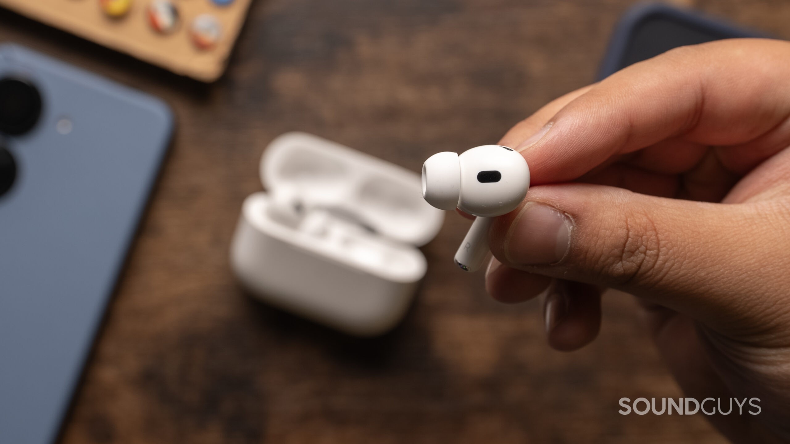 A hand holds the Apple AirPods Pro (2nd generation) bud showing the side.