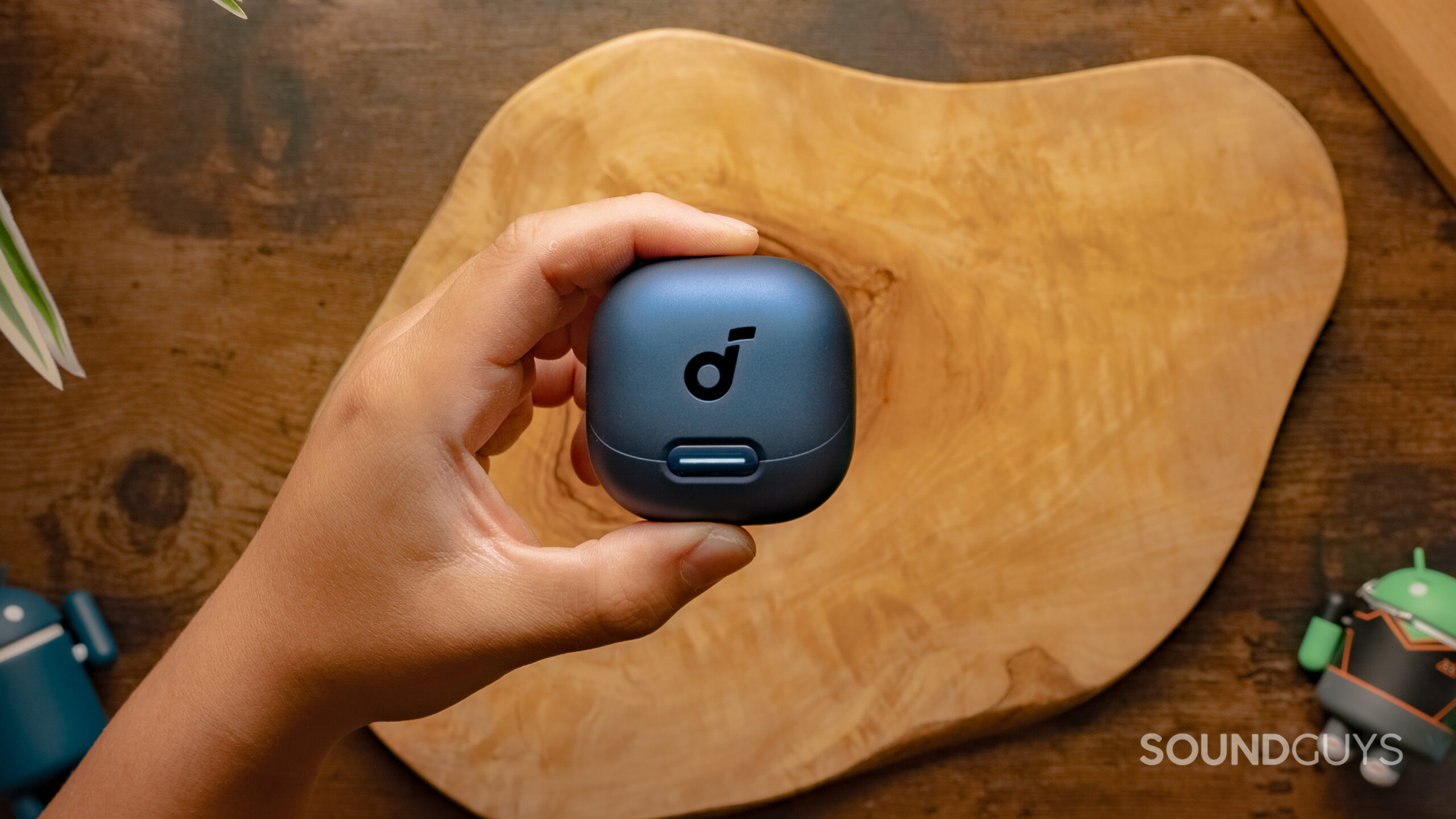 A hand holds the Anker Soundcore Liberty 4 above a wood surface.