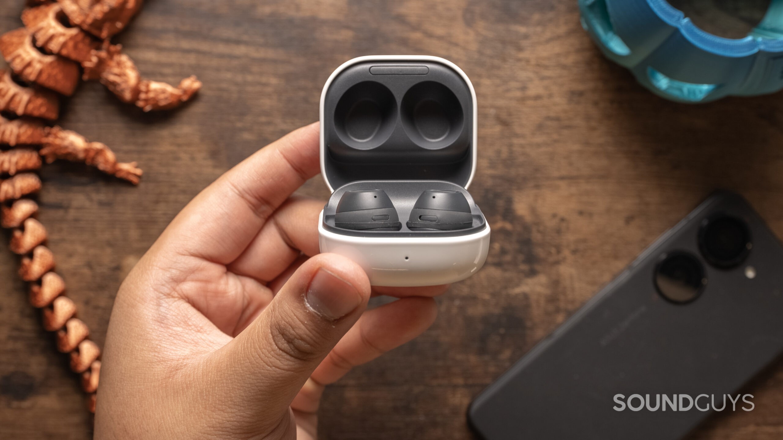 A hand holds the open case of the Samsung Galaxy Buds FE.