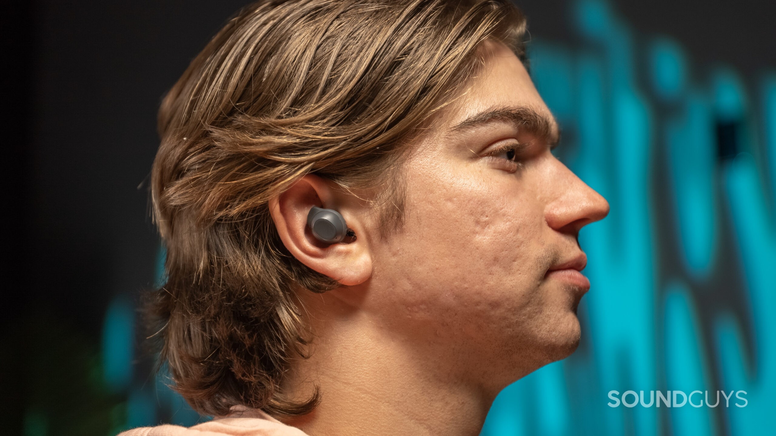 The Samsung Galaxy Buds FE being worn by a man with longer hair.