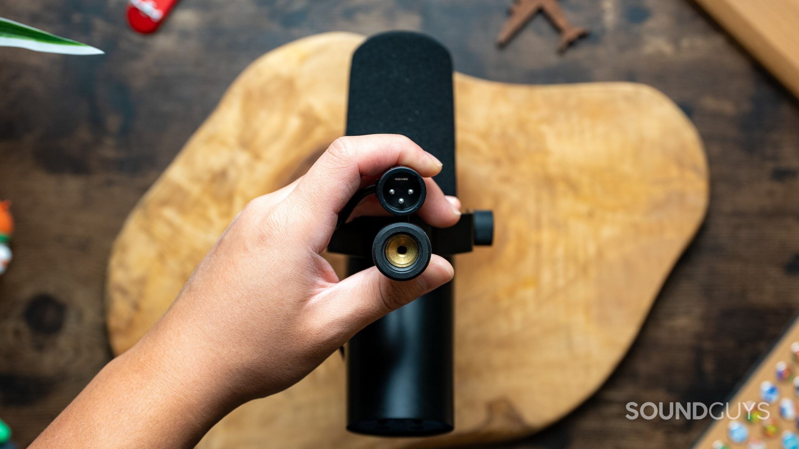 Top down view of a hand holding the SM7dB upside down, showing cable connection and stand threads