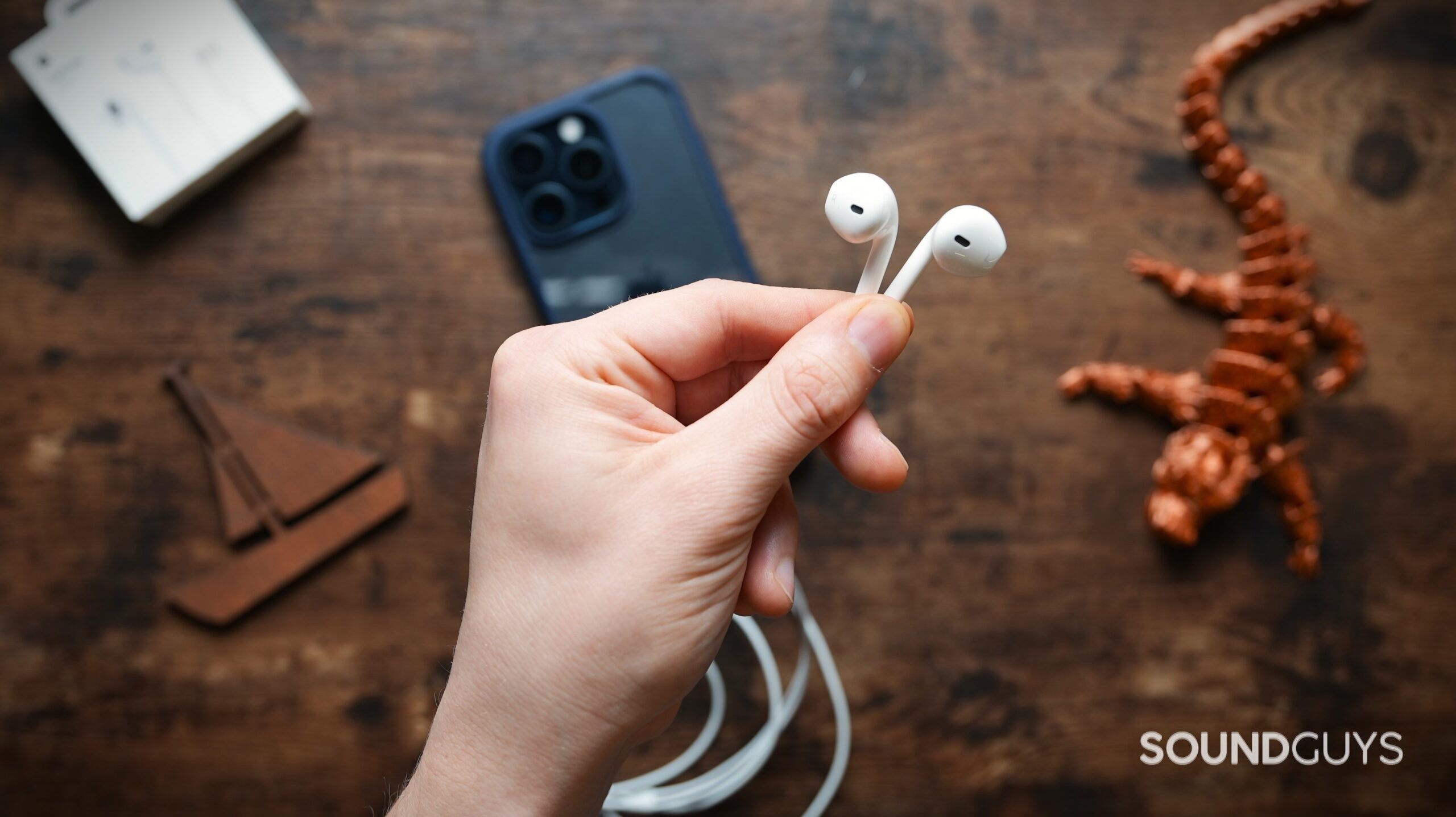 A hand holding the Apple EarPods in their fingertips.