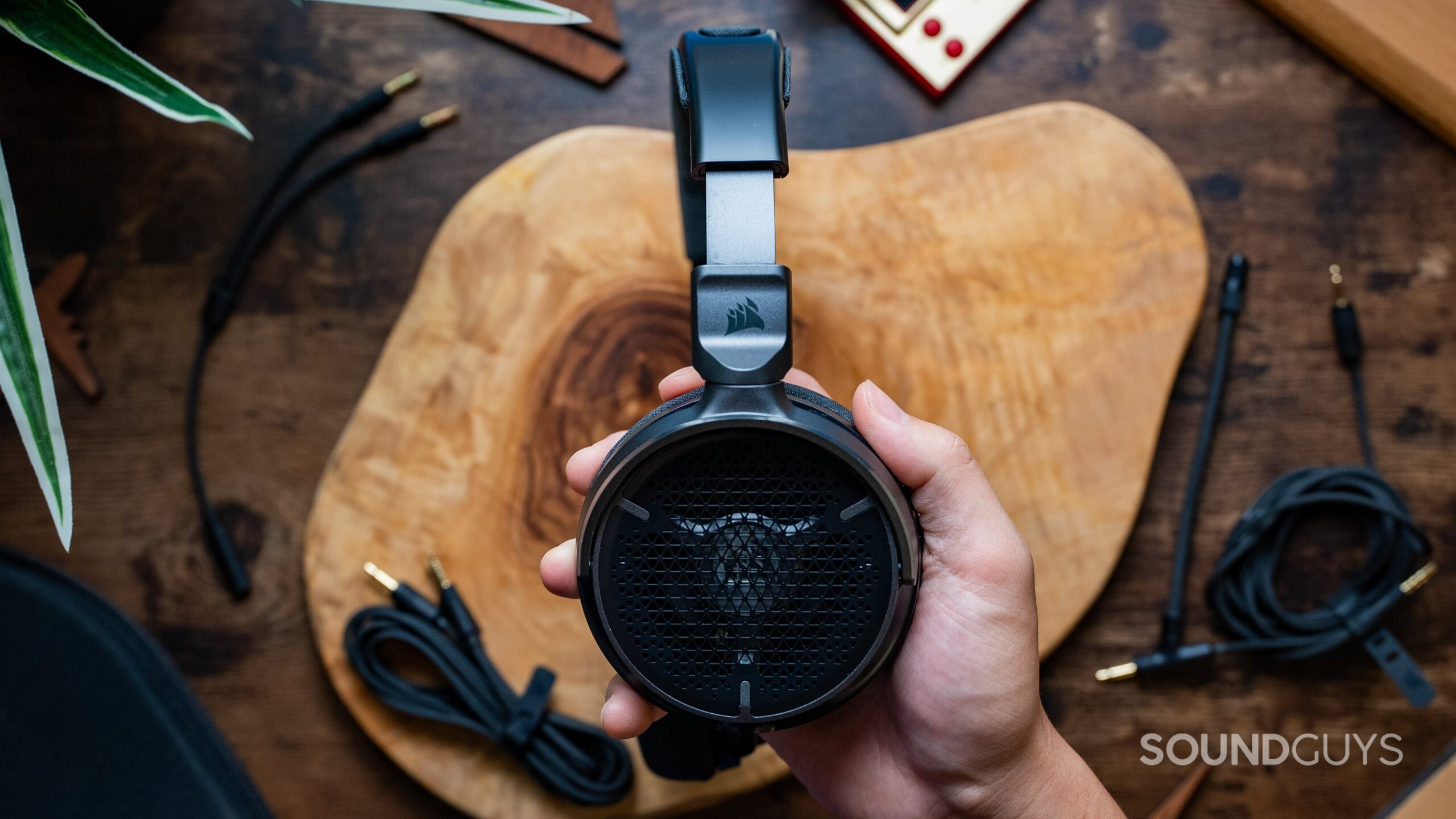Corsair VIRTUOSO PRO headset in a hand over a table.