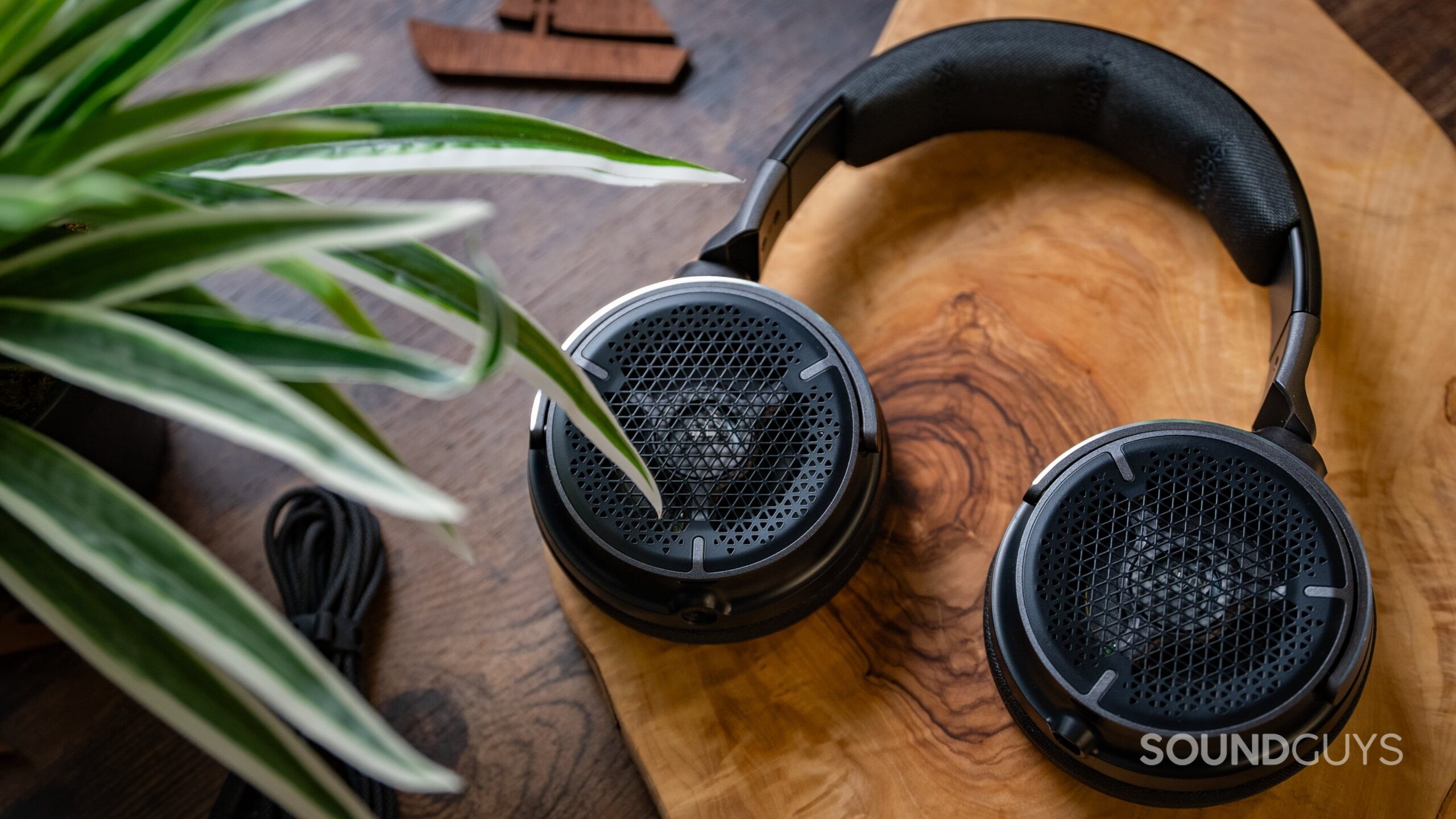 Corsair VIRTUOSO PRO headphones on a table next to a plant.