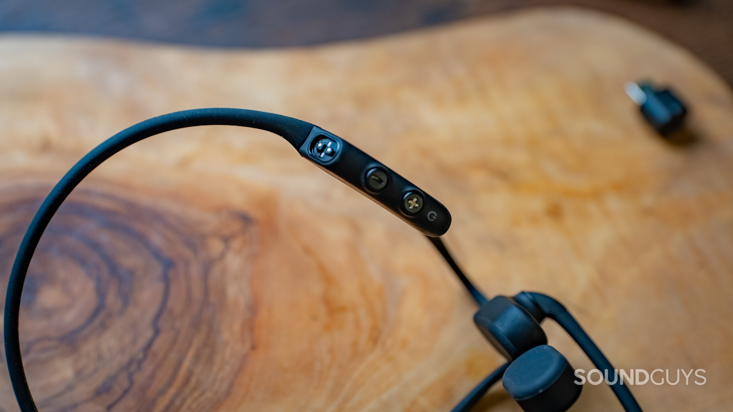 A close up of the volume buttons and proprietary charging port is shown on the Shokz OpenComm2 UC.