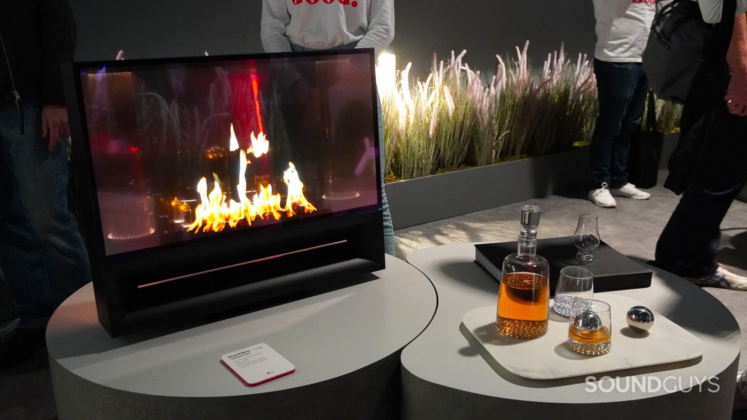 LG DukeBox fireplace on screen with whiskey and glasses