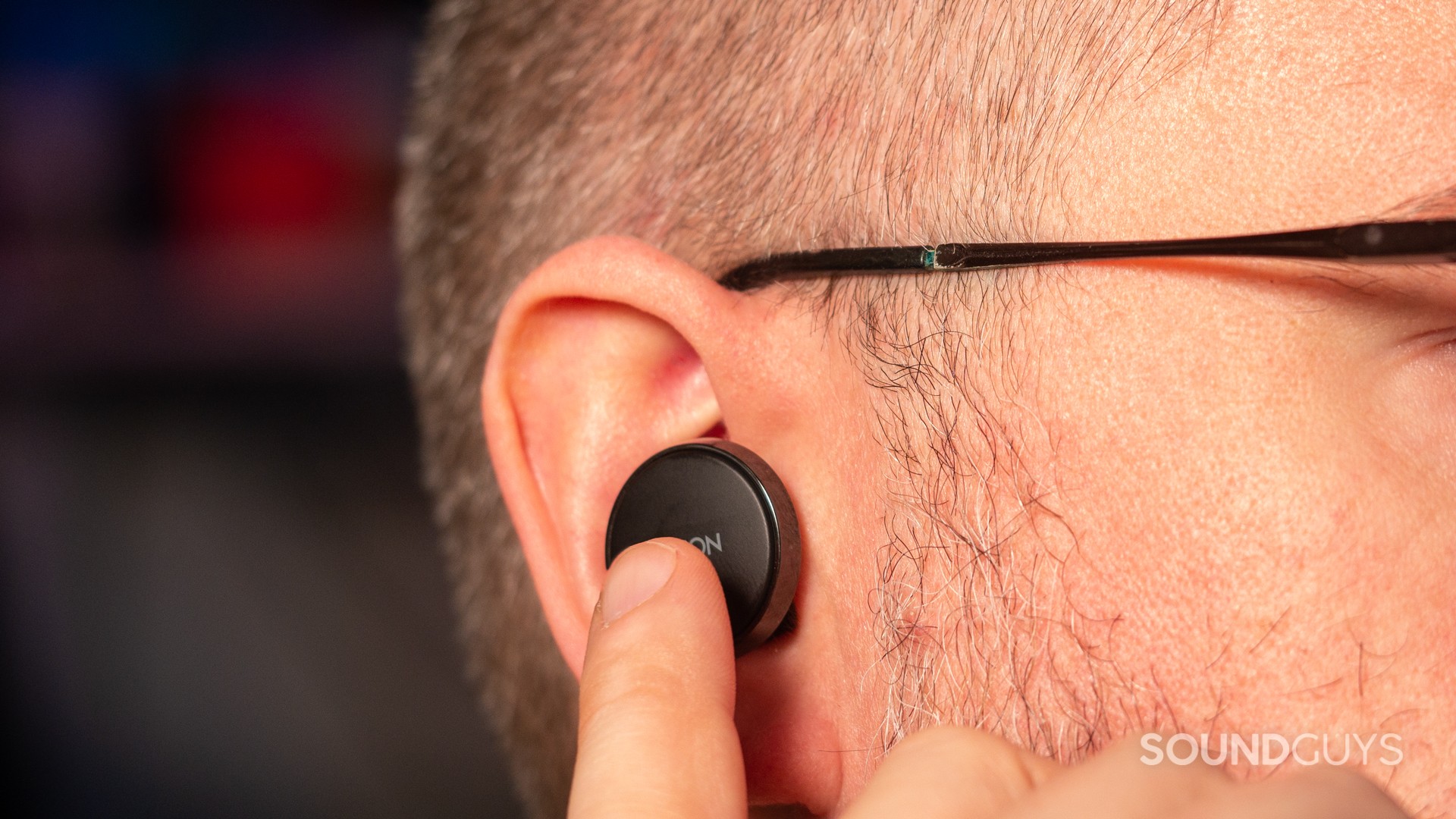 A close-up of a man controlling the Denon PerL Pro earbuds.