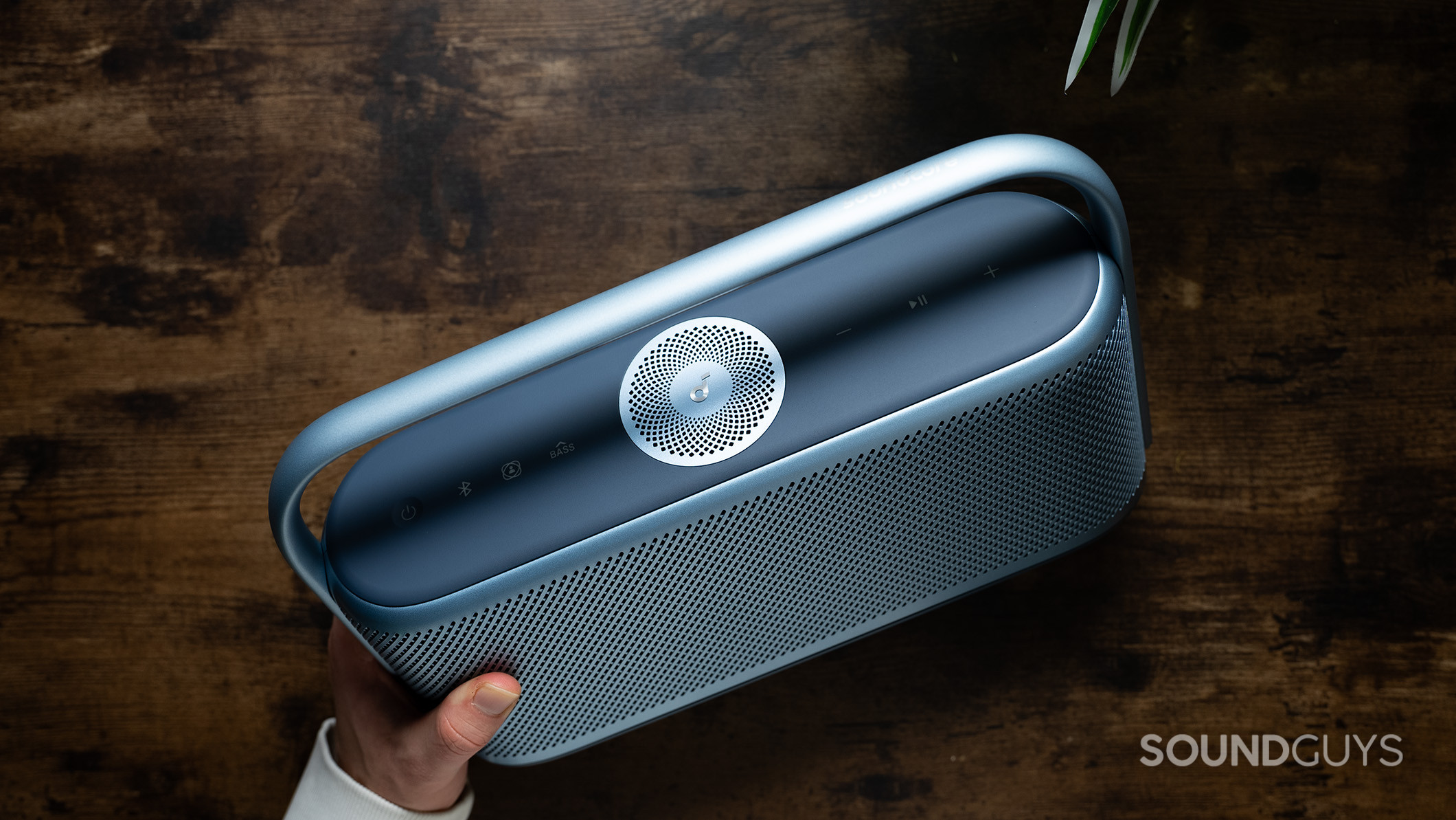 Anker Soundcore Motion X600 speaker held in hand above a table.