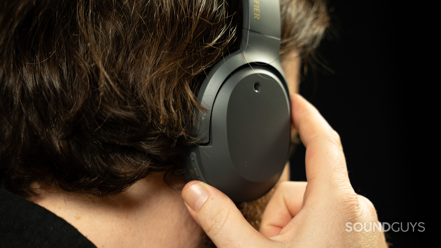 A hand pressing the control buttons on the W820NB Plus headphones.