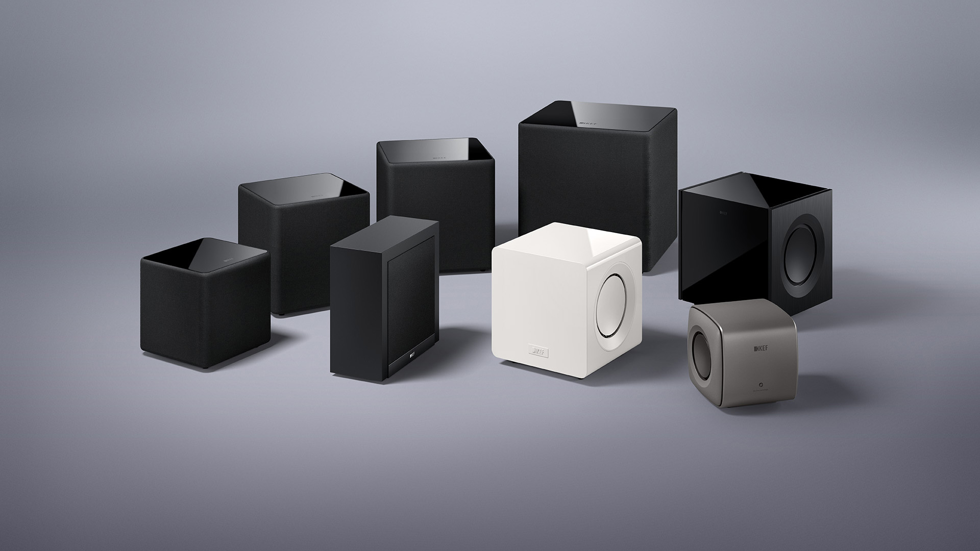 A variety of KEF subwoofers in white and black.