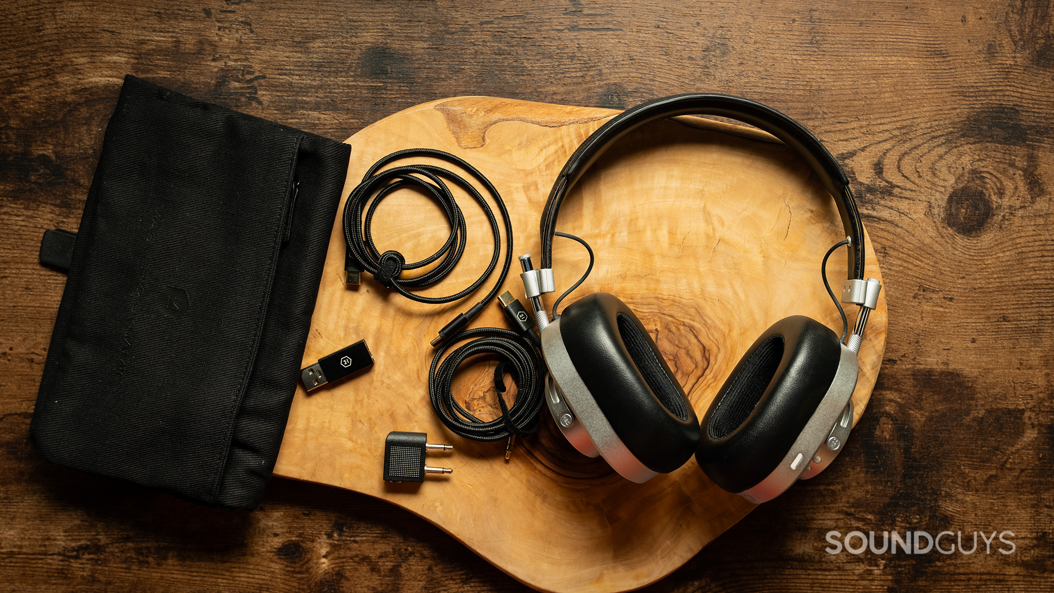 Master &amp; Dynamic MH40 headphones on a table next to the cables, adapters, and case.