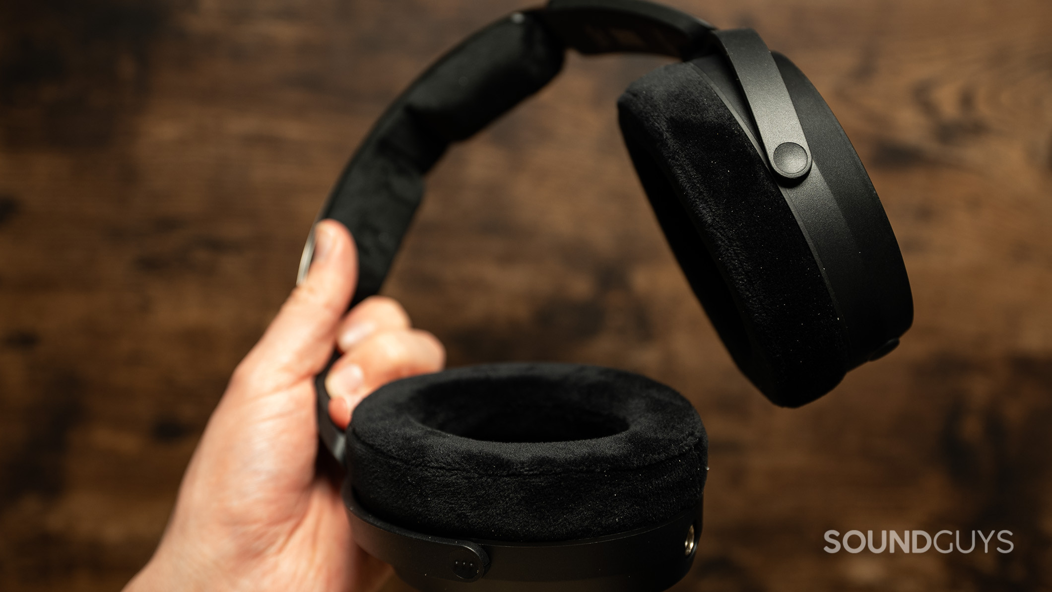 A hand holding the Sennheiser HD490 PRO headphones with the velour ear pads. 