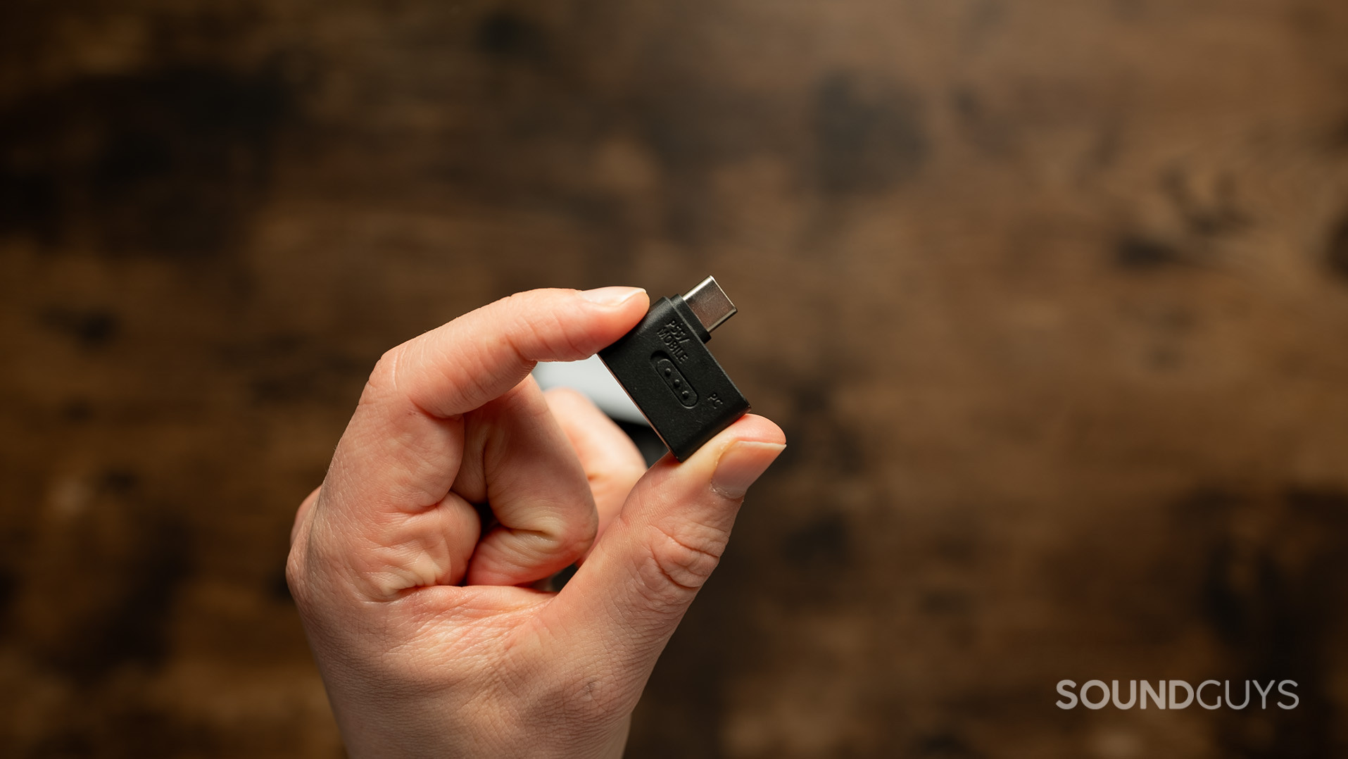 A hand olds the USB-C dongle for the Sony INZONE Buds.