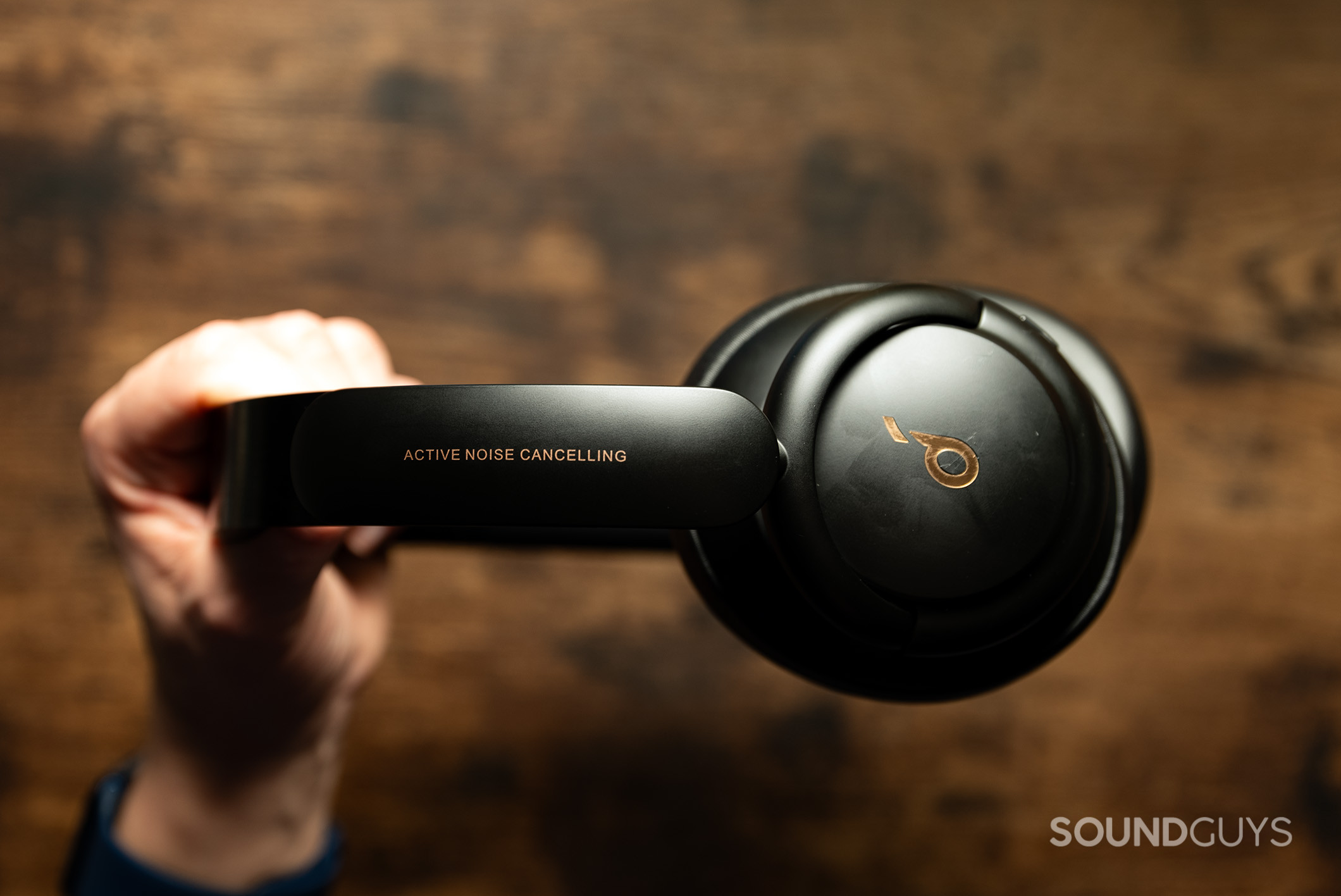 Anker Soundcore Life Q30 headphones held in a hand above a wood table.