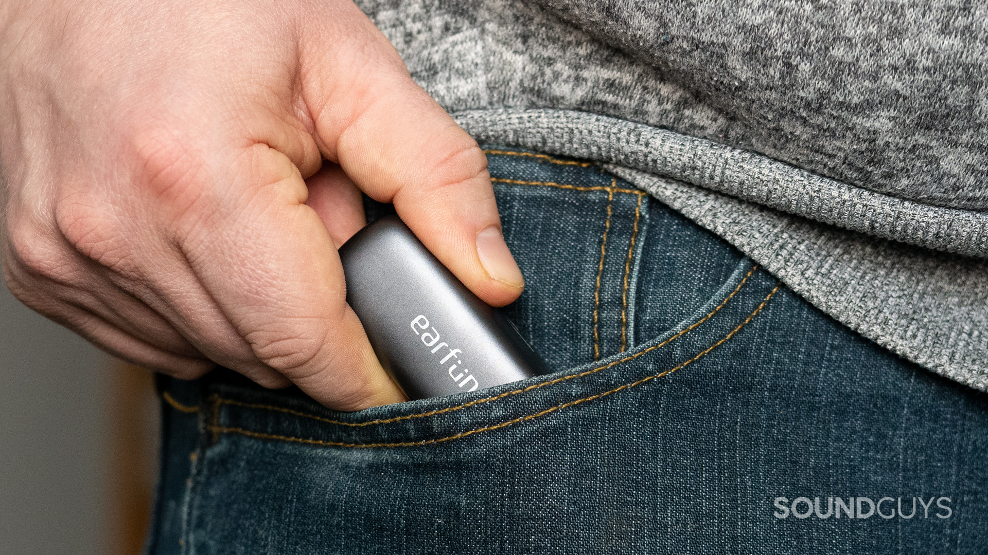 A photo of a man shoving the EarFun Free Pro 3 into his pocket.