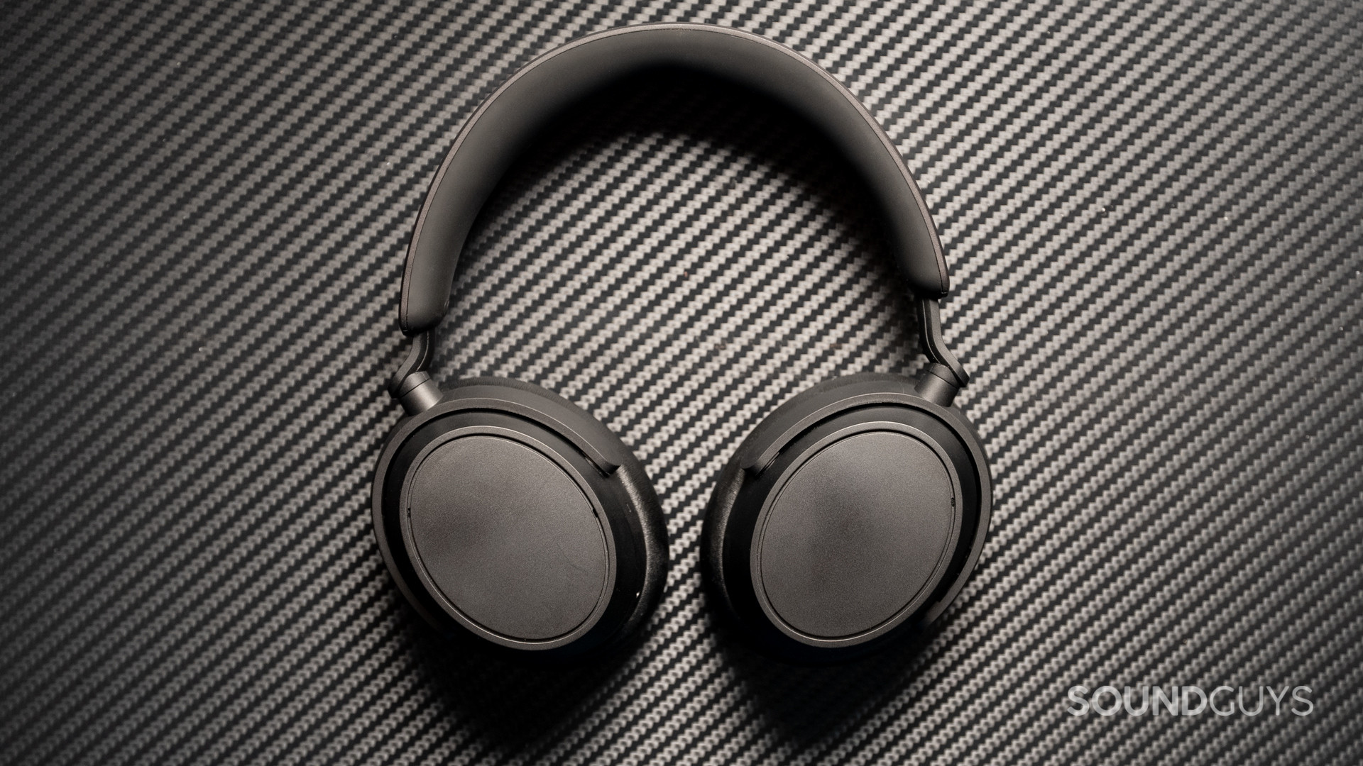 A photo of the Sennheiser ACCENTUM Plus sitting atop a carbon fiber surface.