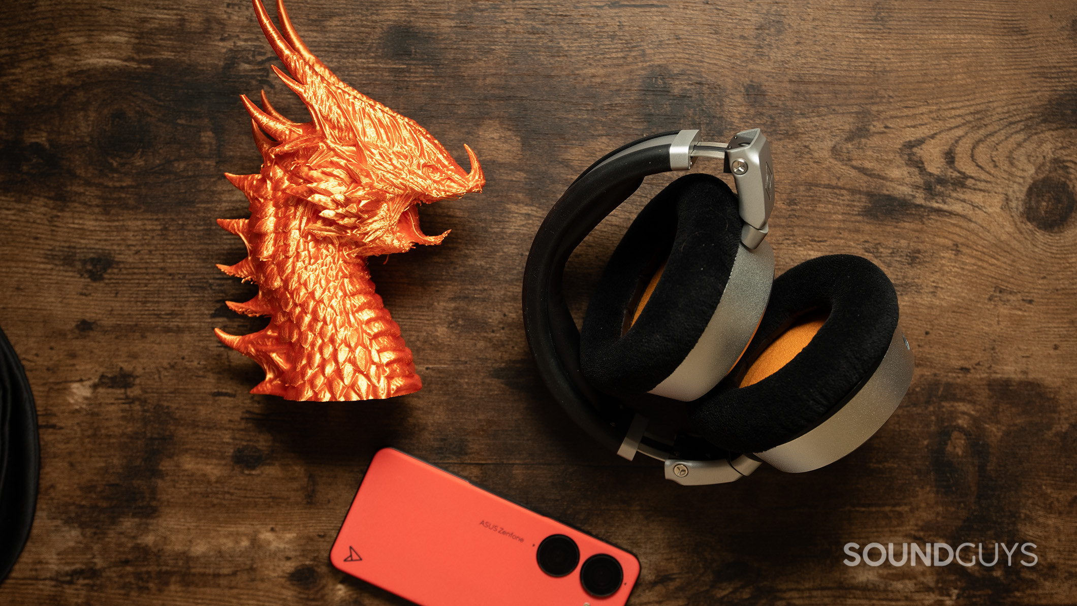 Neumann NDH 30 headphones on a desk next to a plastic dragon and smartphone. 