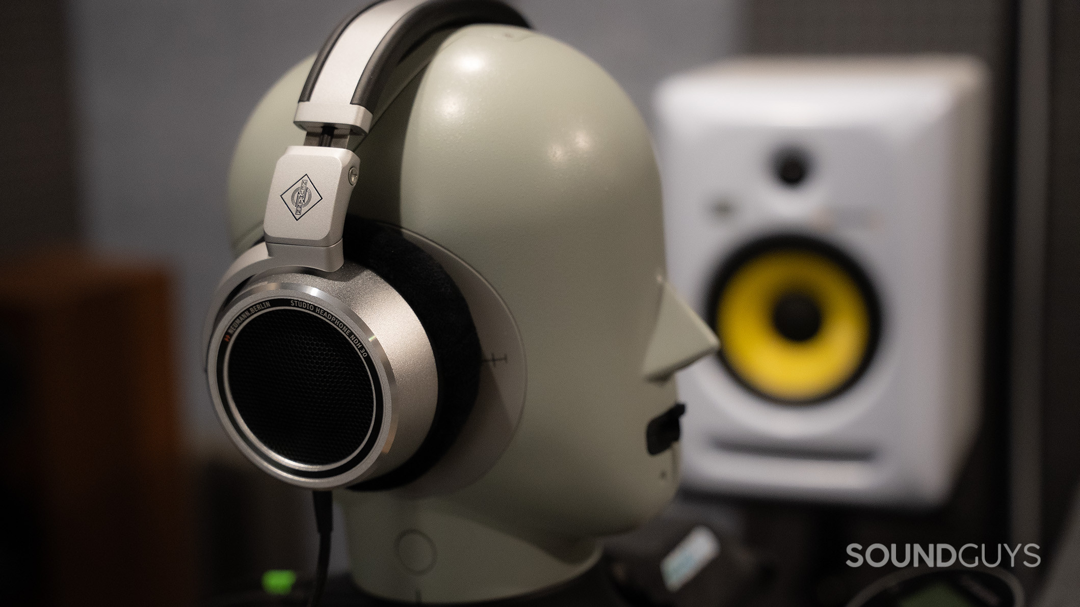 Neumann NDH 30 headphones on a testing head next to a monitor speaker.