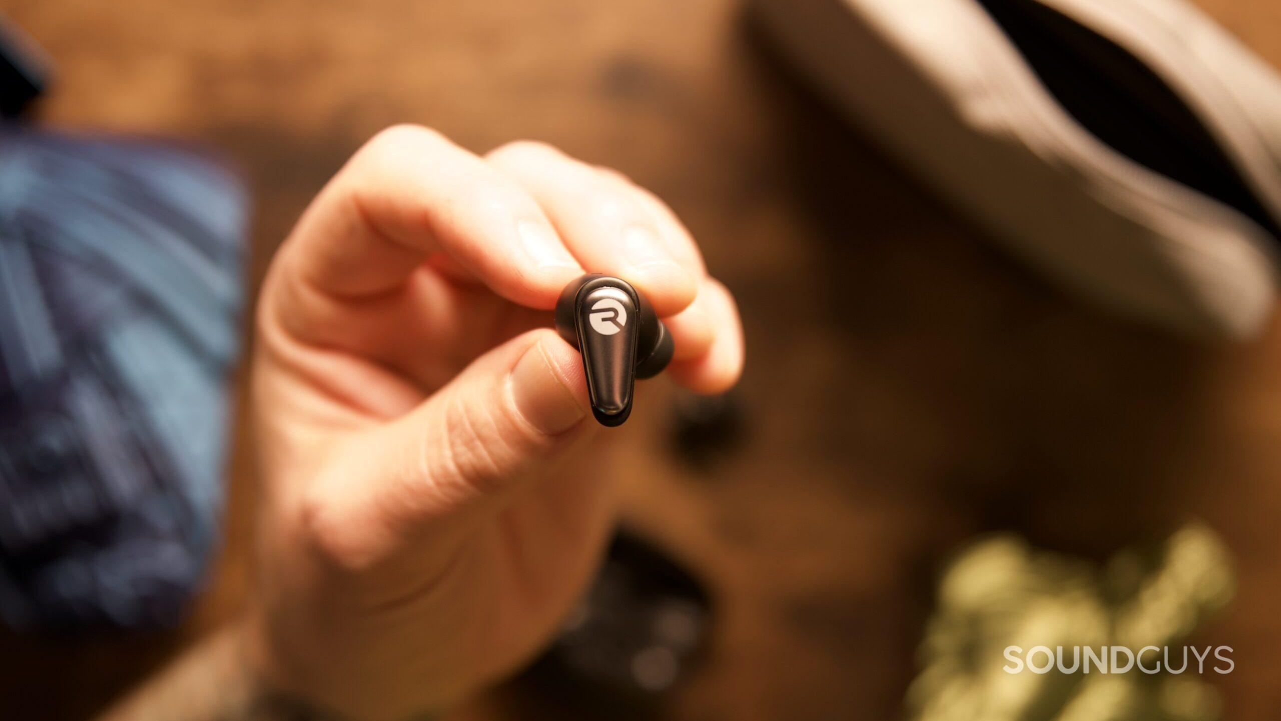 A hand holding a singular Raycon Everyday Earbud Pro. 