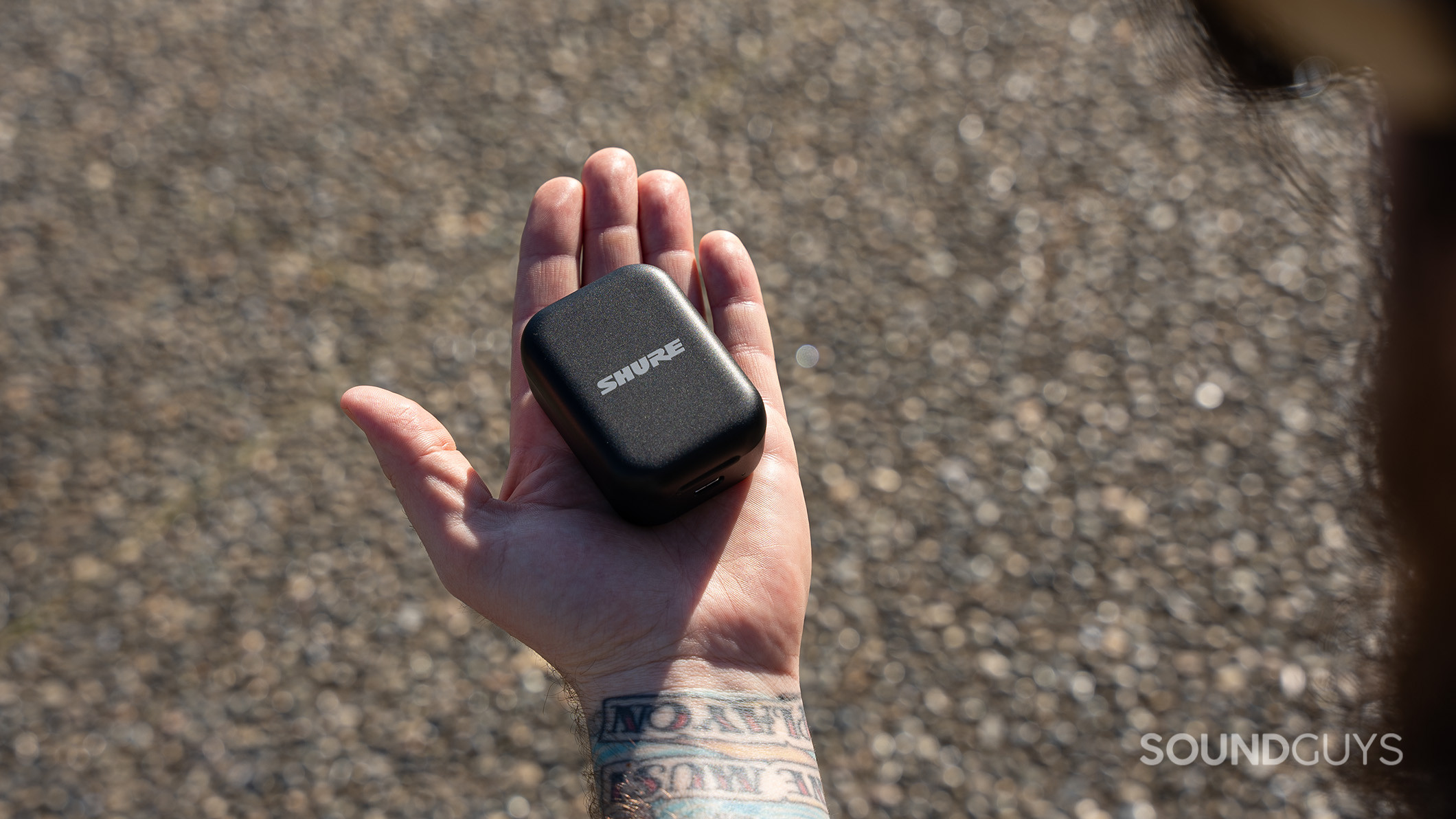 A Shure MoveMic charging case on the palm of an open hand