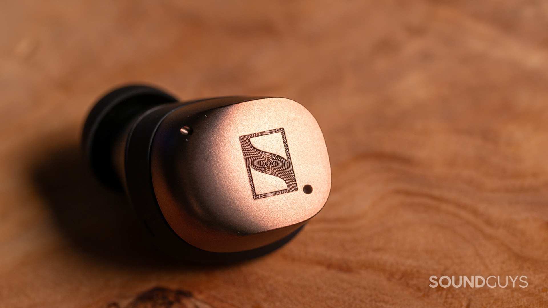 A close-up photo of the Sennheiesr MOMENTUM True Wireless 4's earbud on a wooden table.