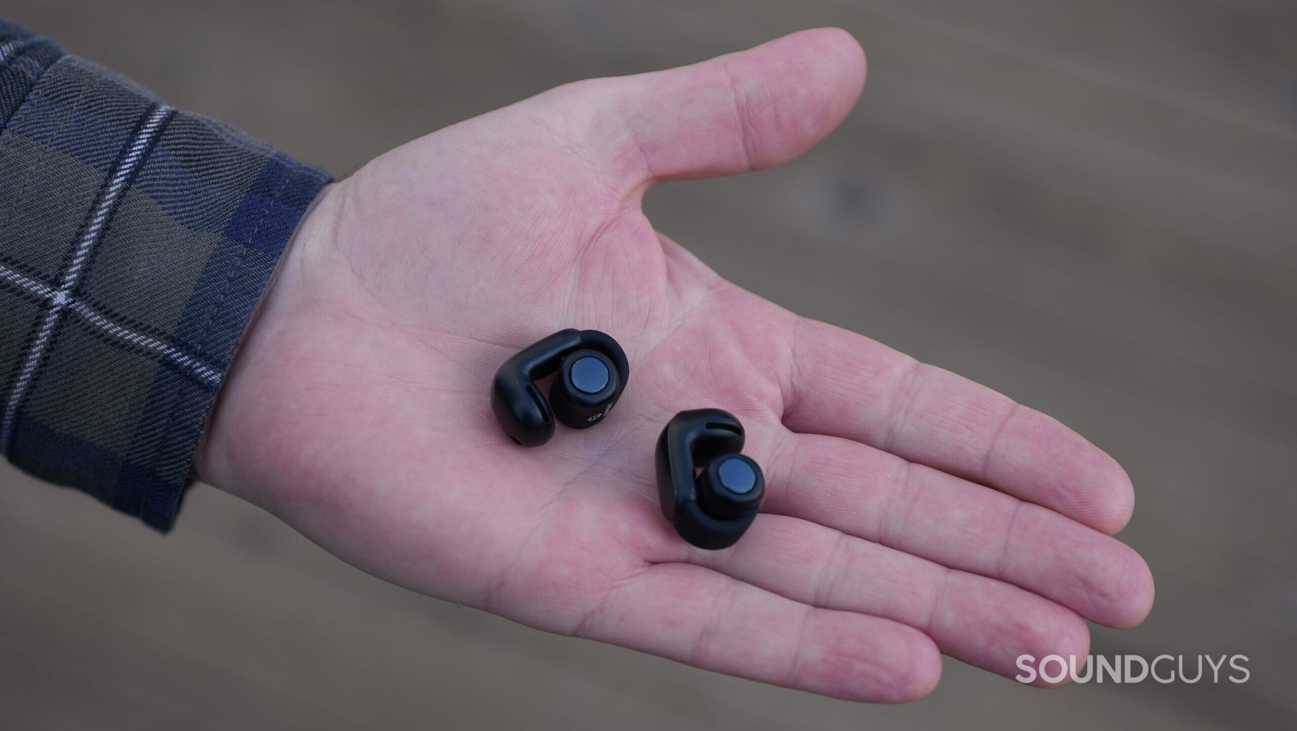 A photo of the Bose Ultimate Open Earbuds resting on an open hand