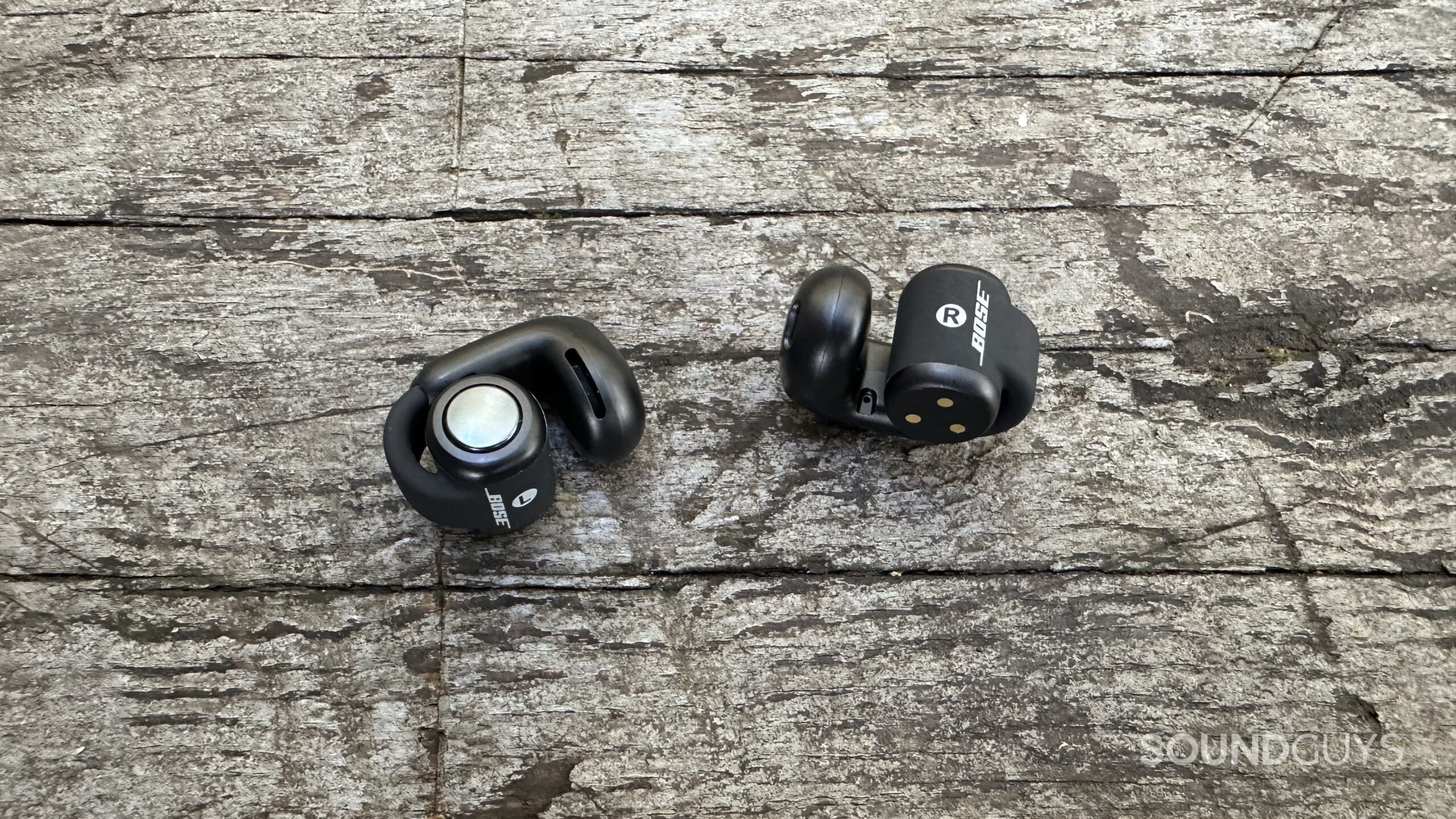 Bose Ultra Open Earbuds on a grey bench