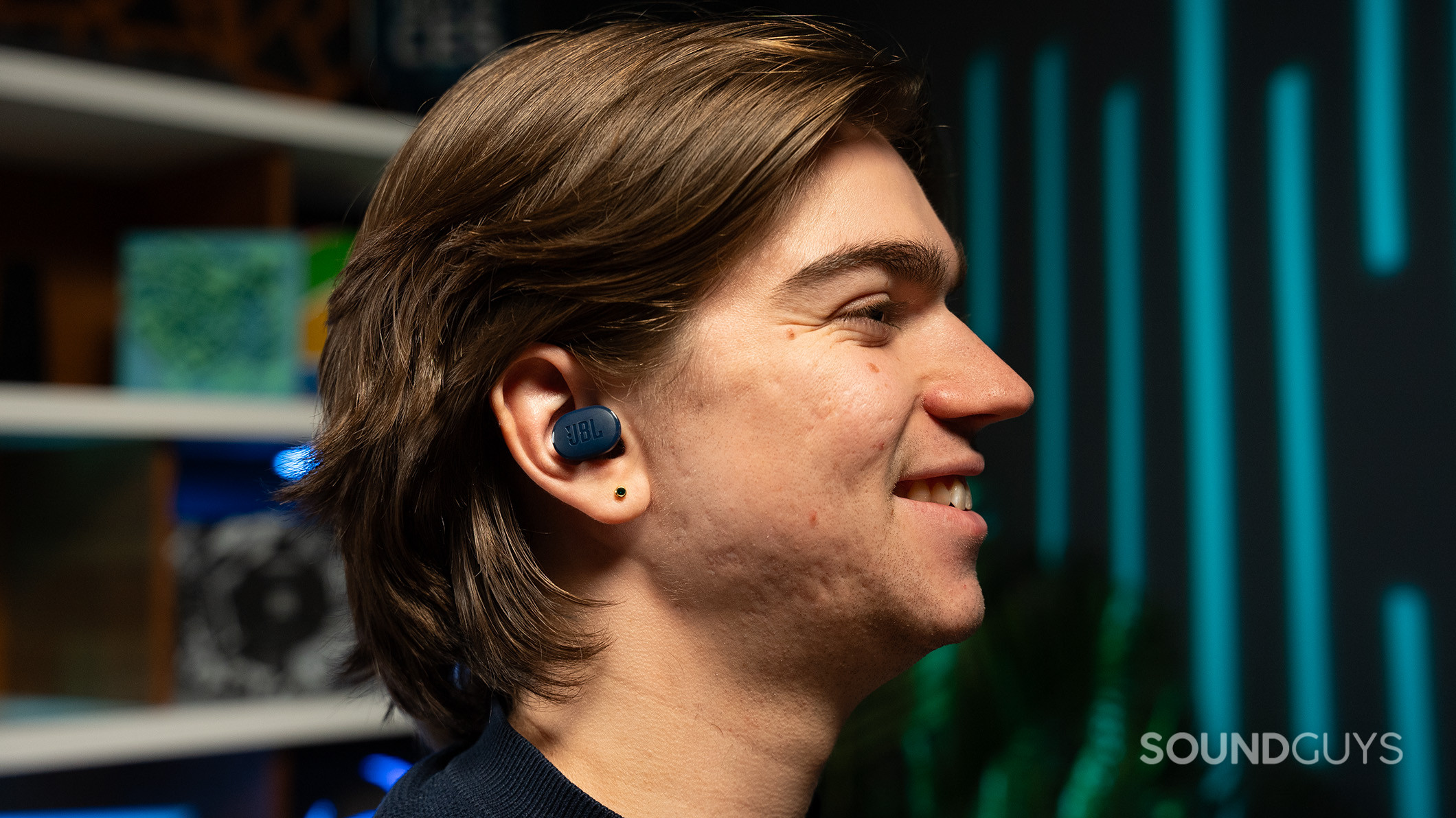 A man wearing a JBL Tune Buds earbud in his right ear. 