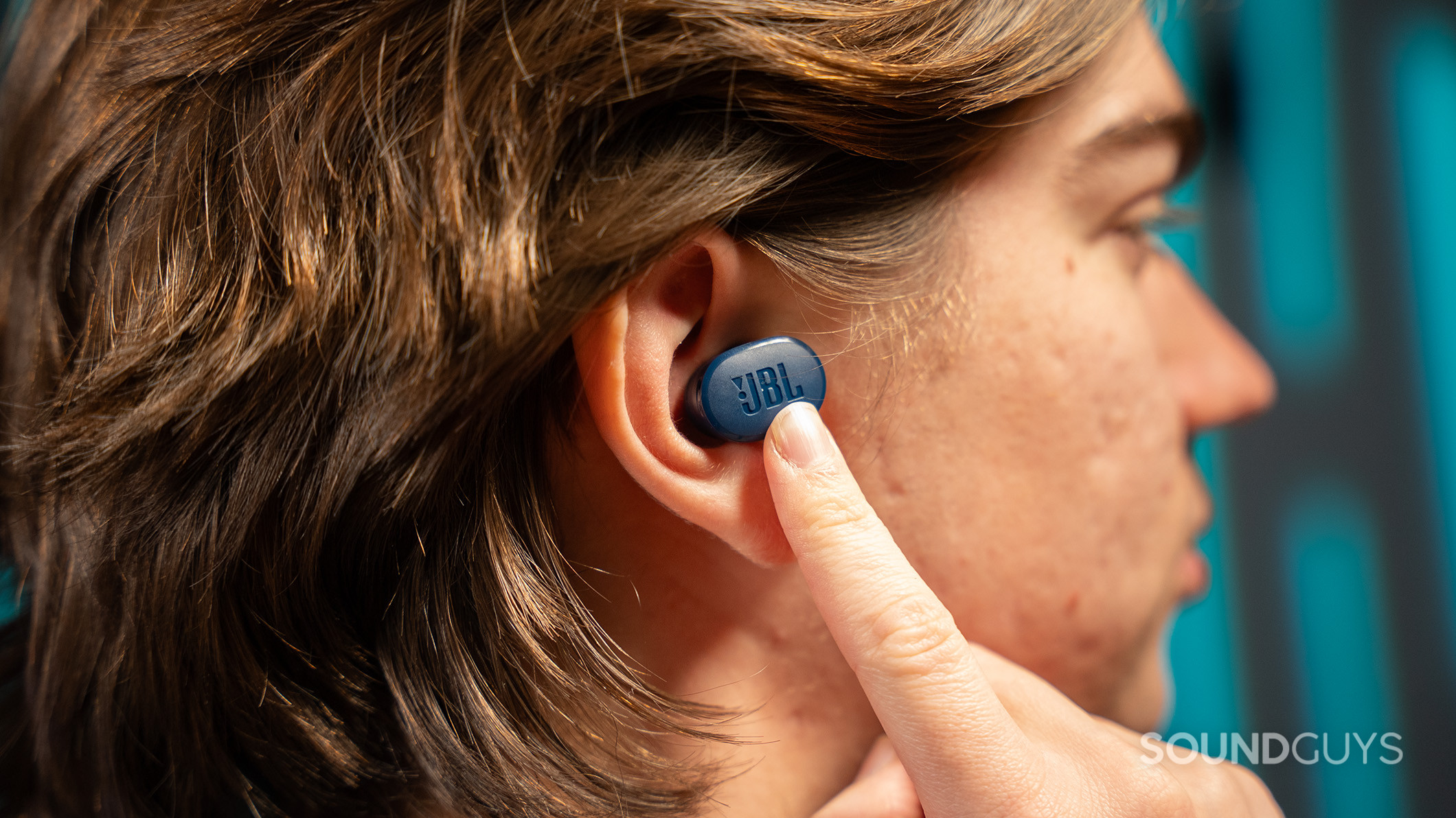 A man pushes the JBL Tune Buds earbud into his ear. 