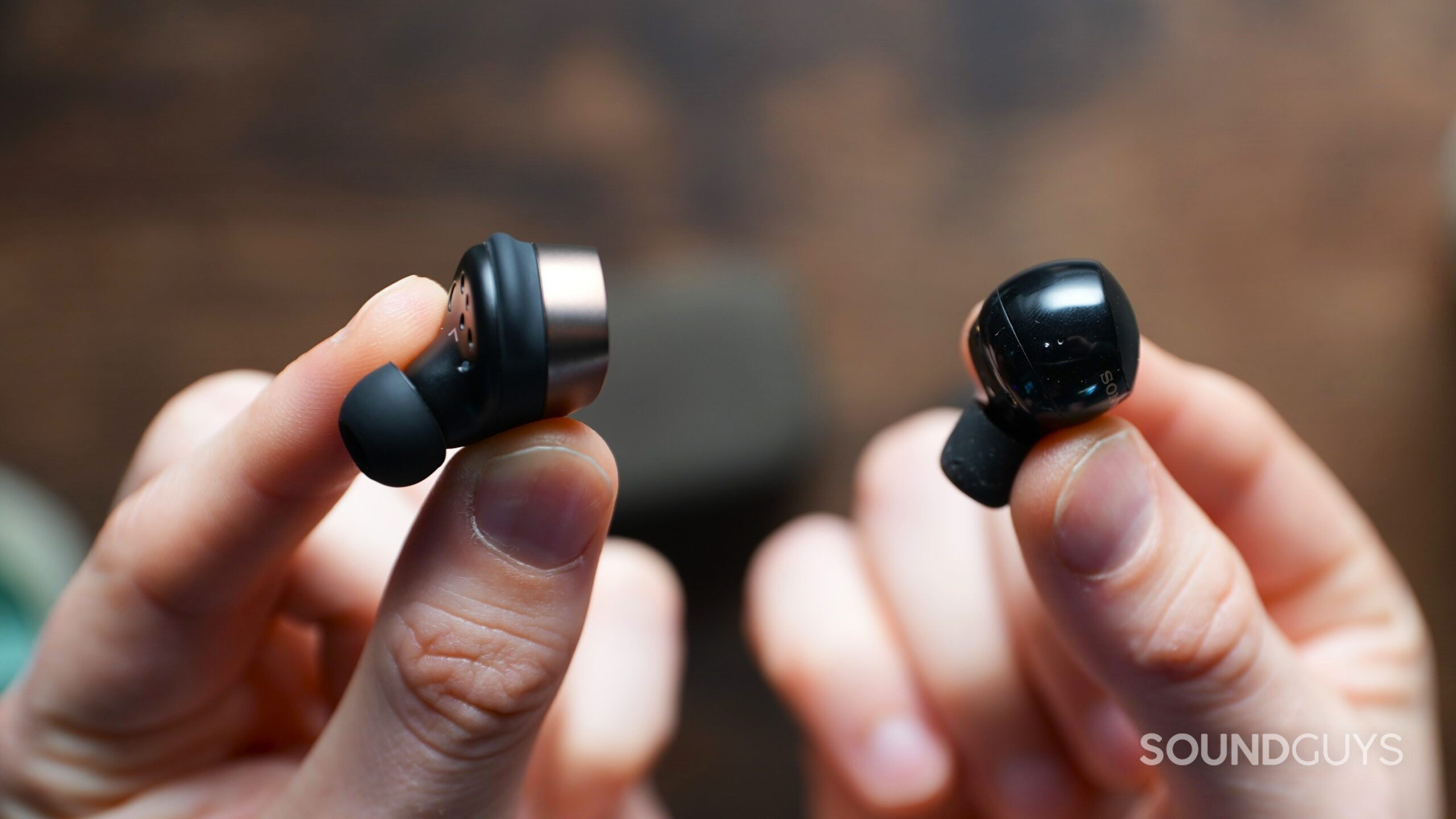 Hands holding the Sennheiser Momentum True Wireless 4 beside the Sony WF-1000XM5 earbuds