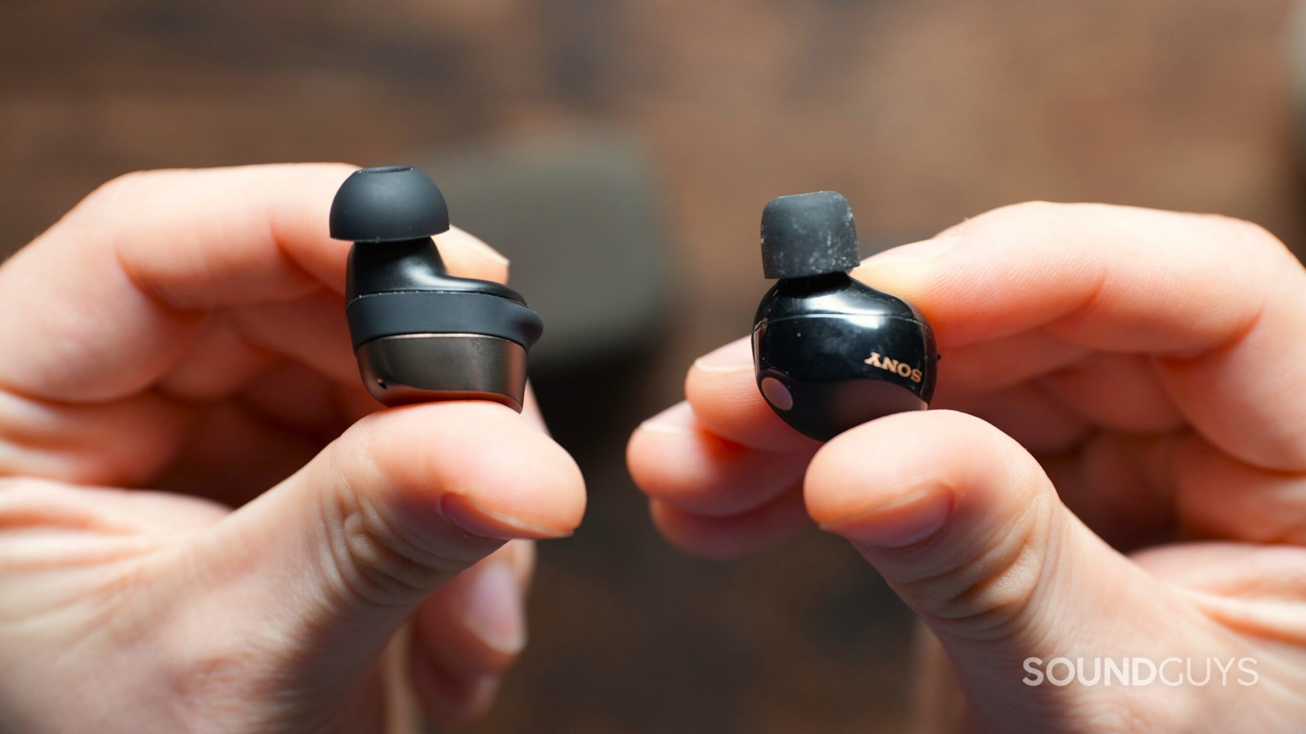 Hands holding the Sennheiser Momentum True Wireless 4 beside the Sony WF-1000XM5 earbuds